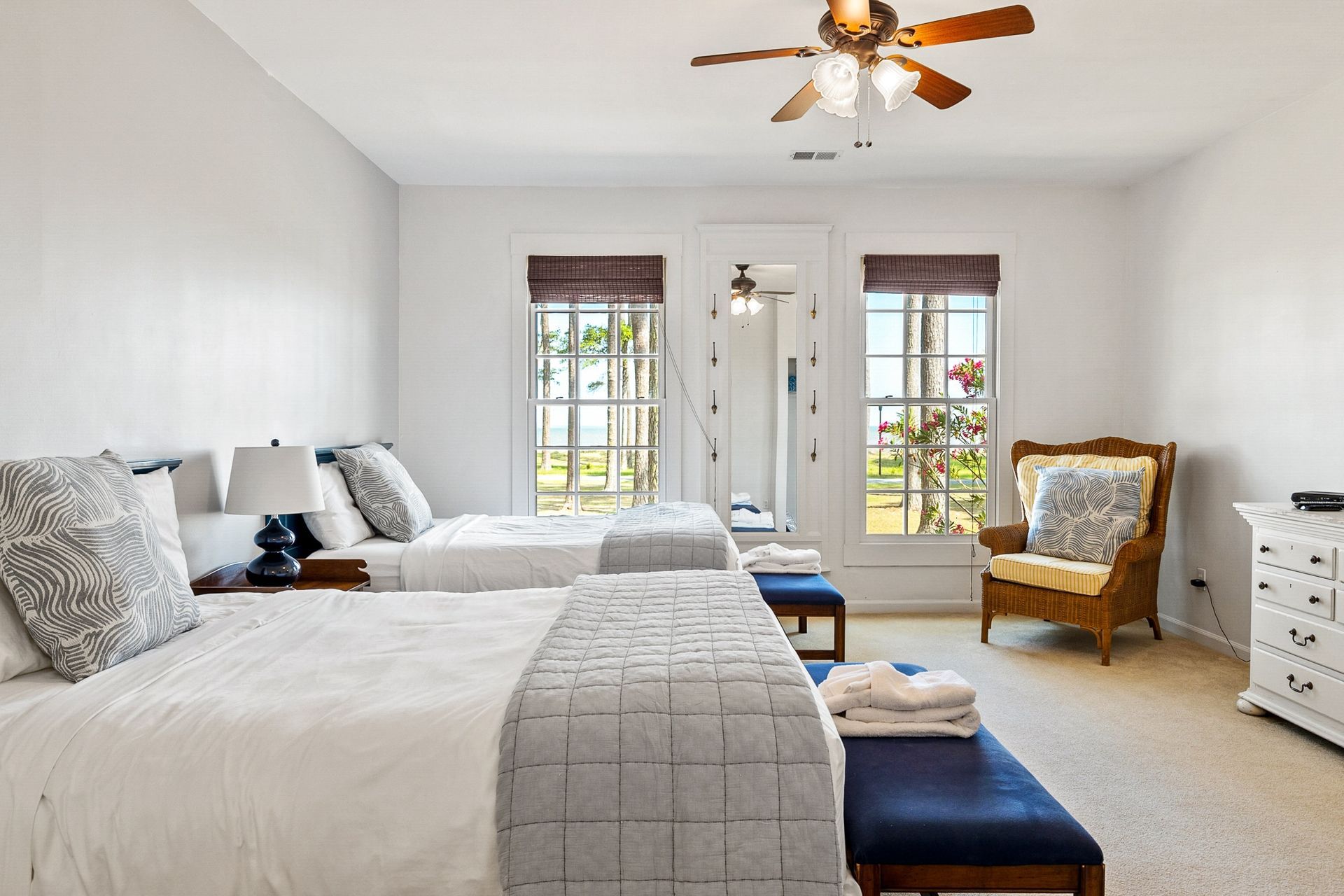 A bedroom with two beds , a chair , a dresser and a ceiling fan.