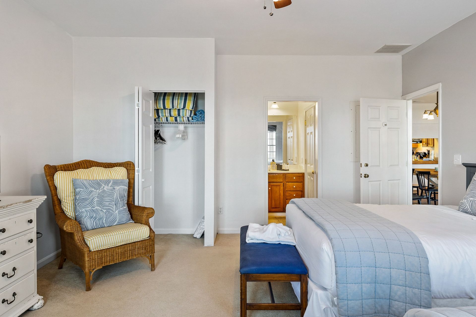 A bedroom with a bed , chair , dresser and a bench.