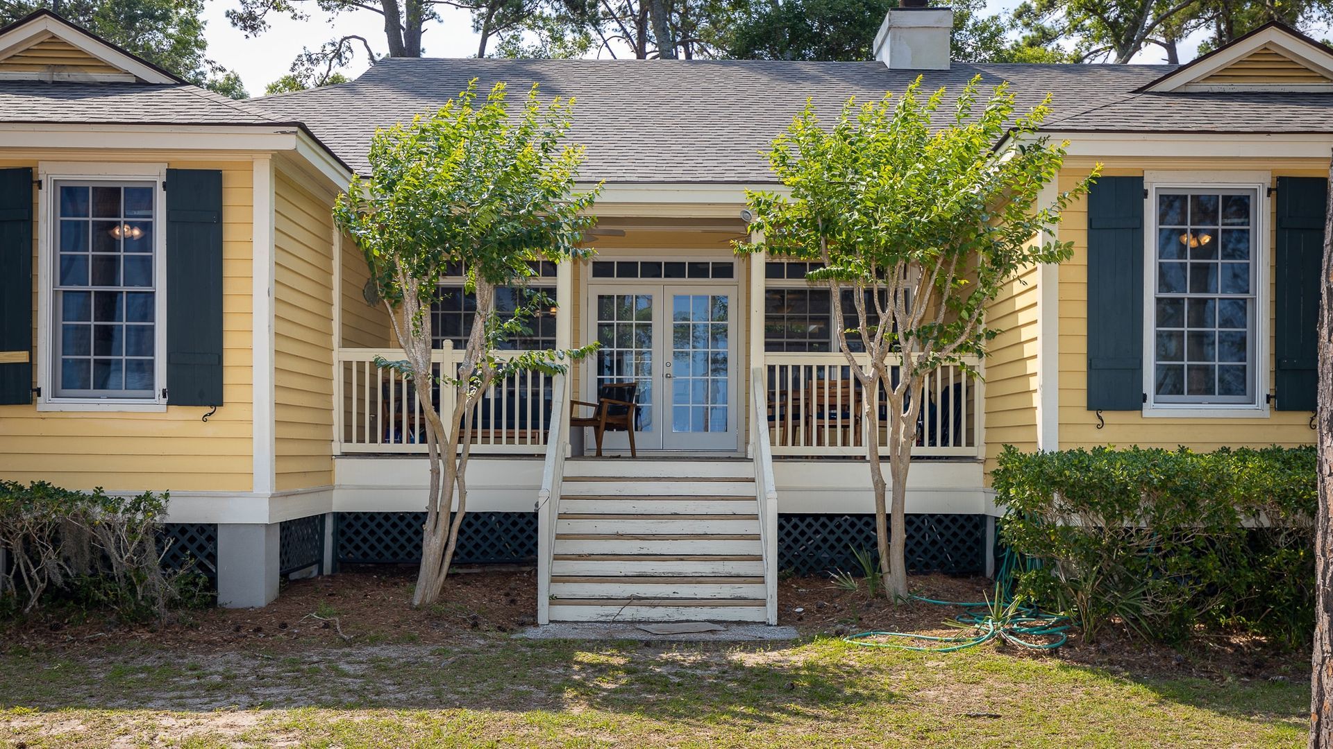 A yellow house with green shutters and a porch