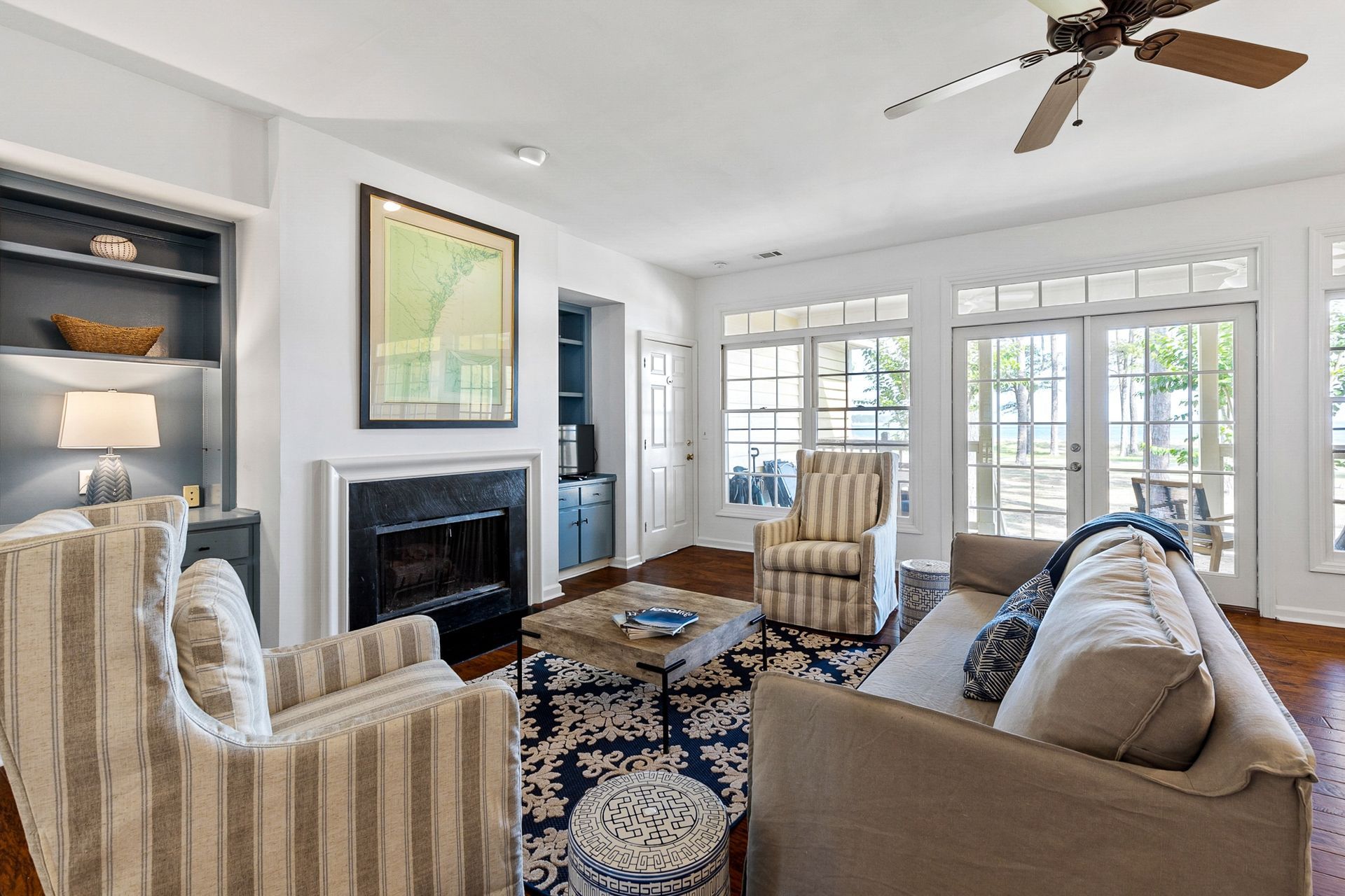 A living room with a couch , chairs , a fireplace and a ceiling fan.