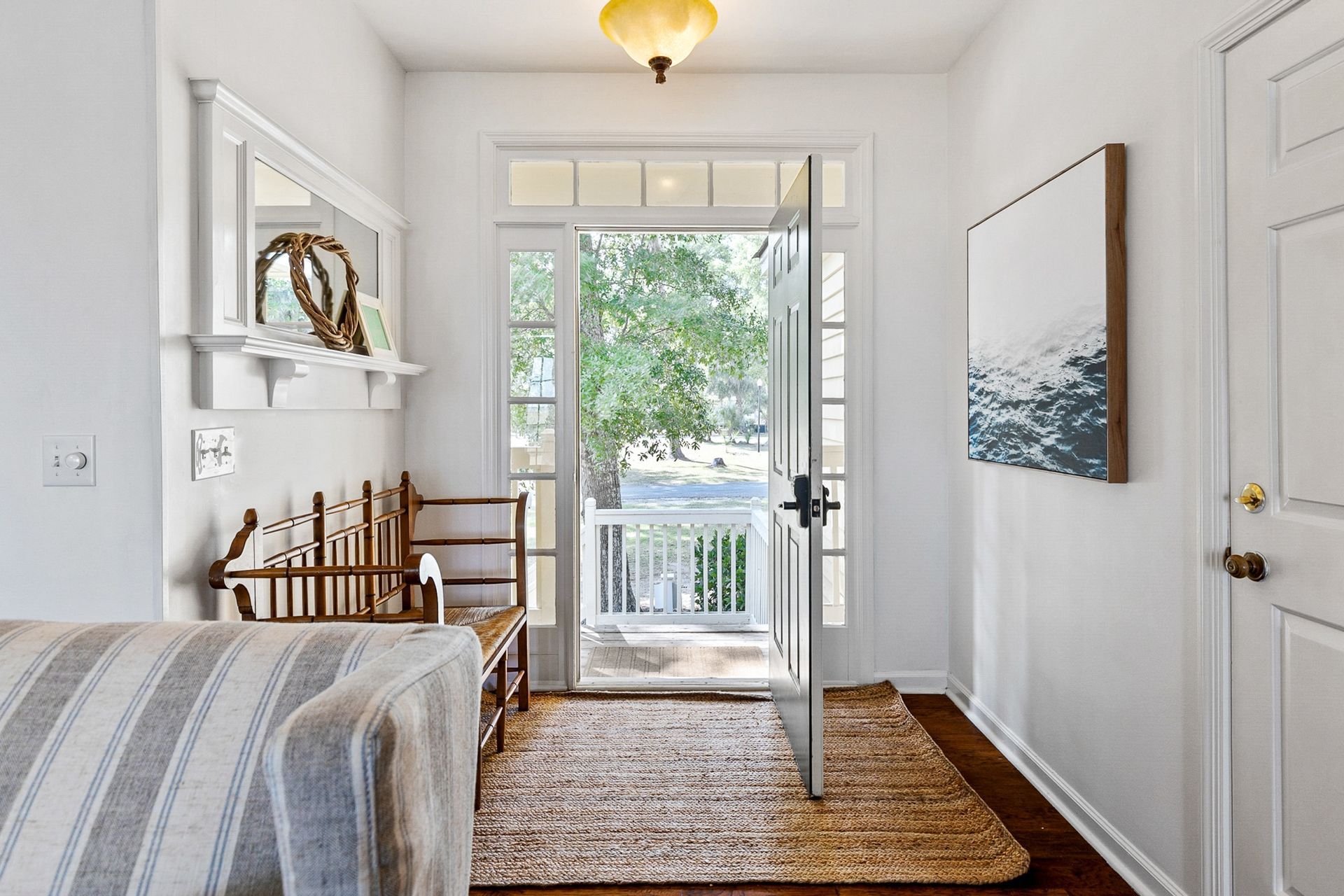 A bedroom with a bed , bench , rug and a painting on the wall.