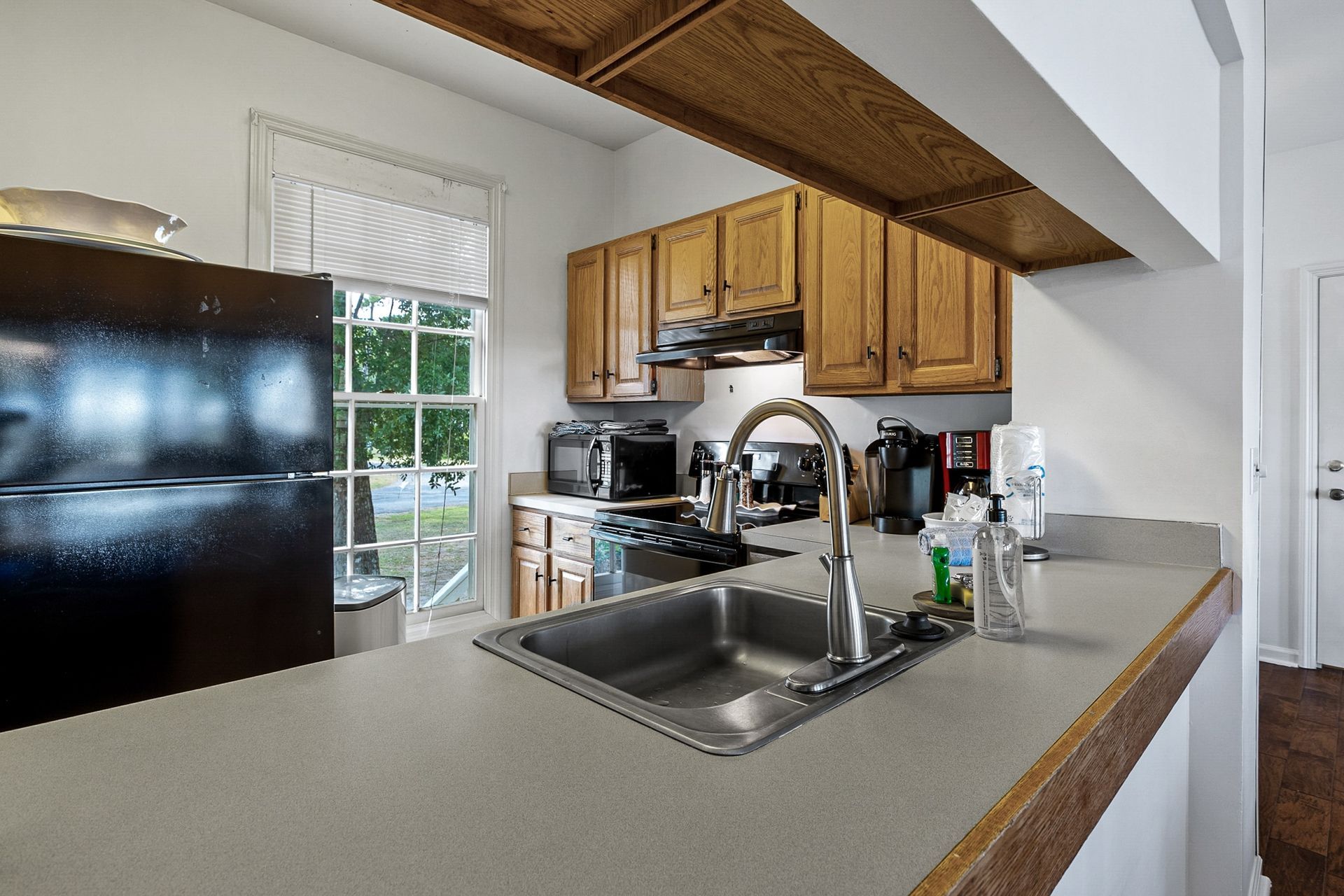 A kitchen with a sink , refrigerator , stove and microwave.