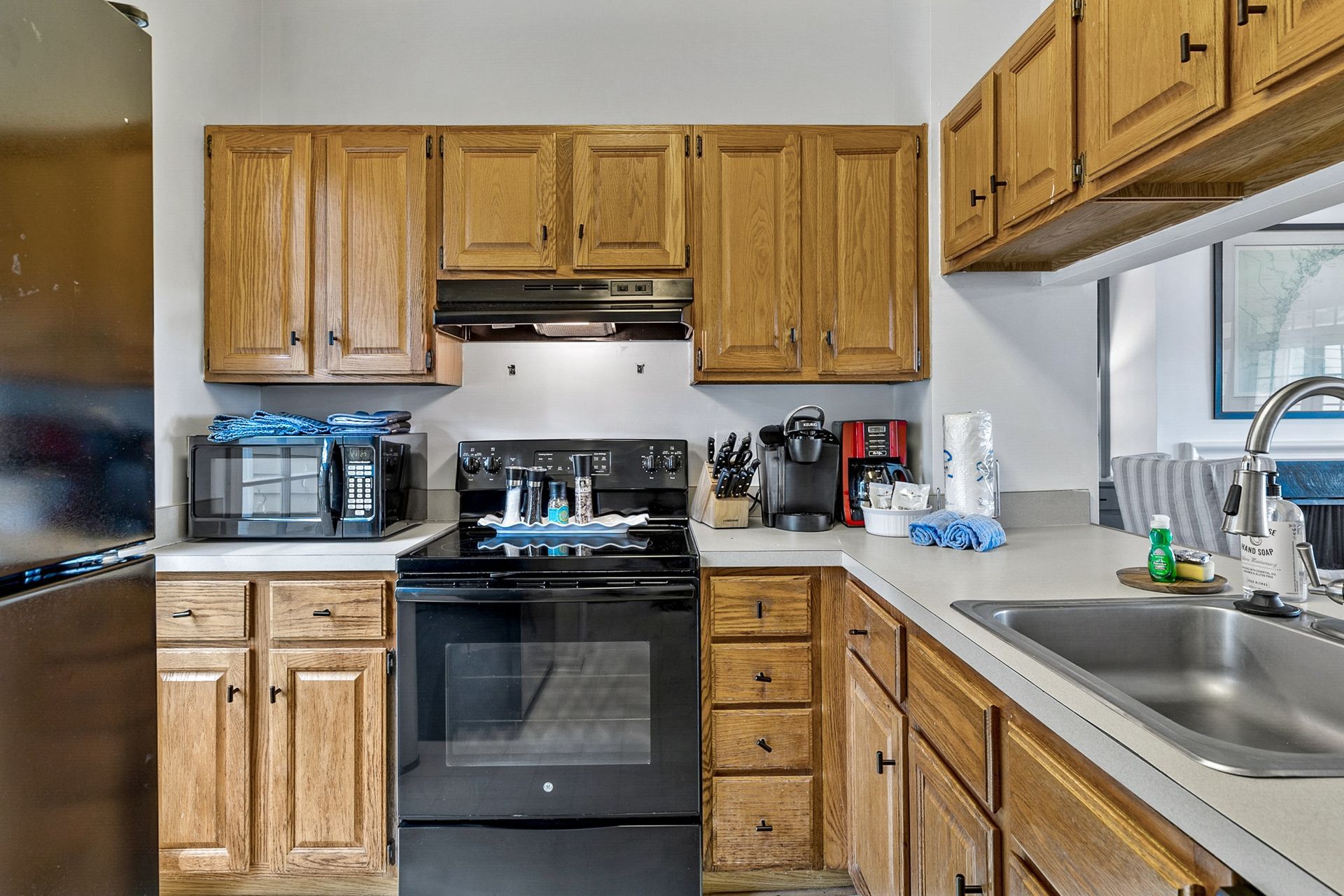 A kitchen with wooden cabinets , a stove , a sink , and a microwave.