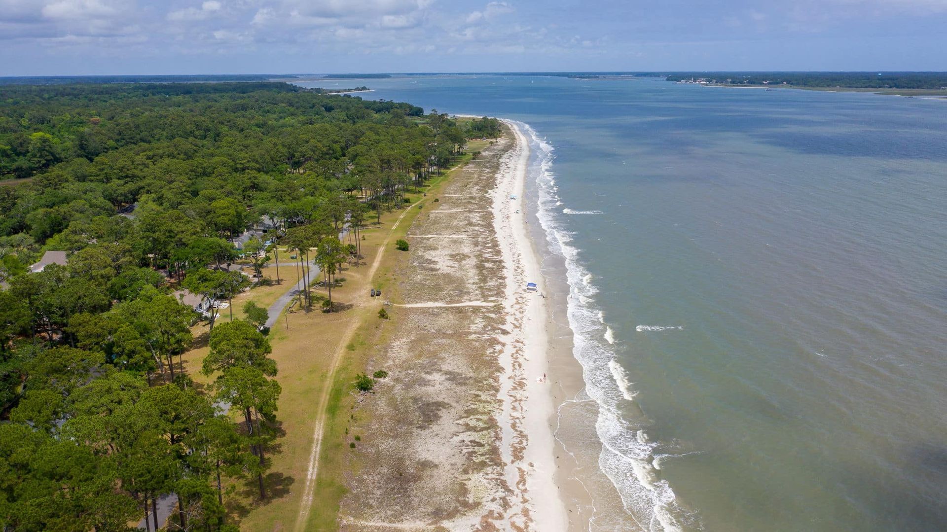 An aerial view of a beach surrounded by trees and a body of water.