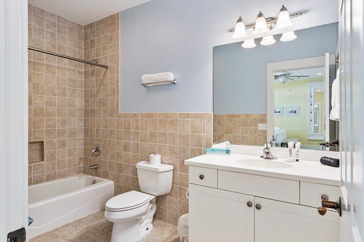 A bathroom with a toilet , sink , tub and mirror.