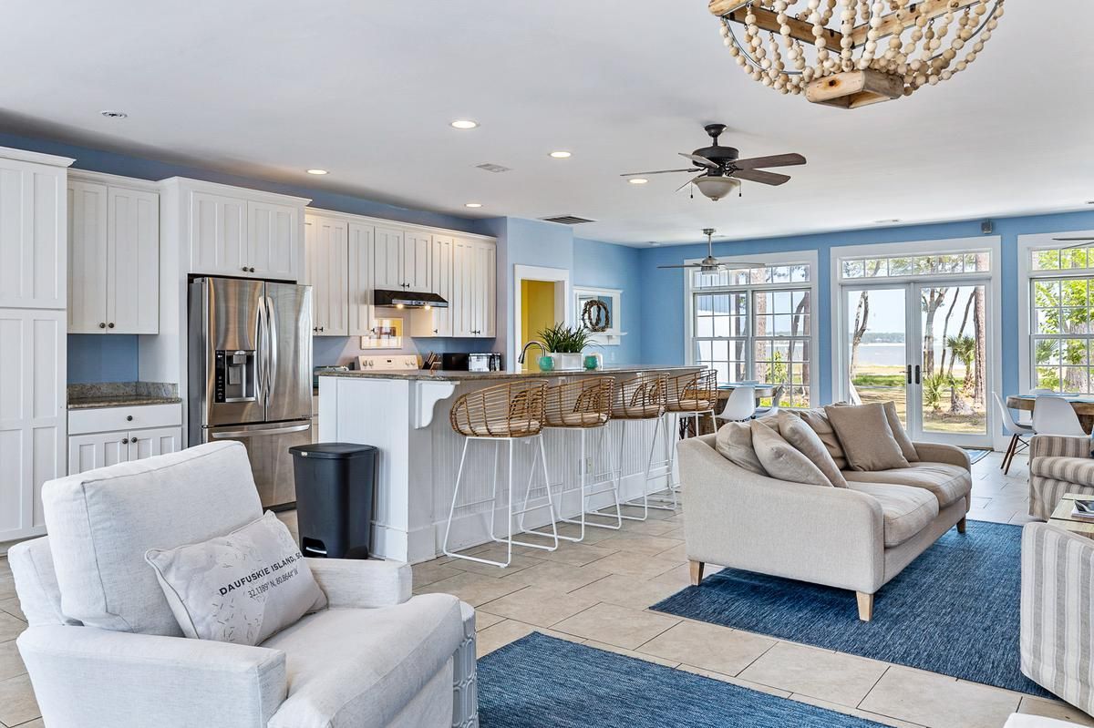 A living room with a couch , chairs , and a chandelier.