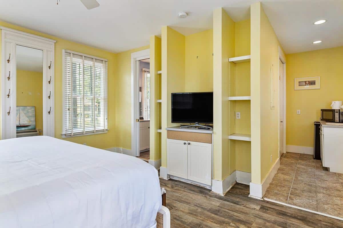 A bedroom with a bed , television , shelves and a mirror.