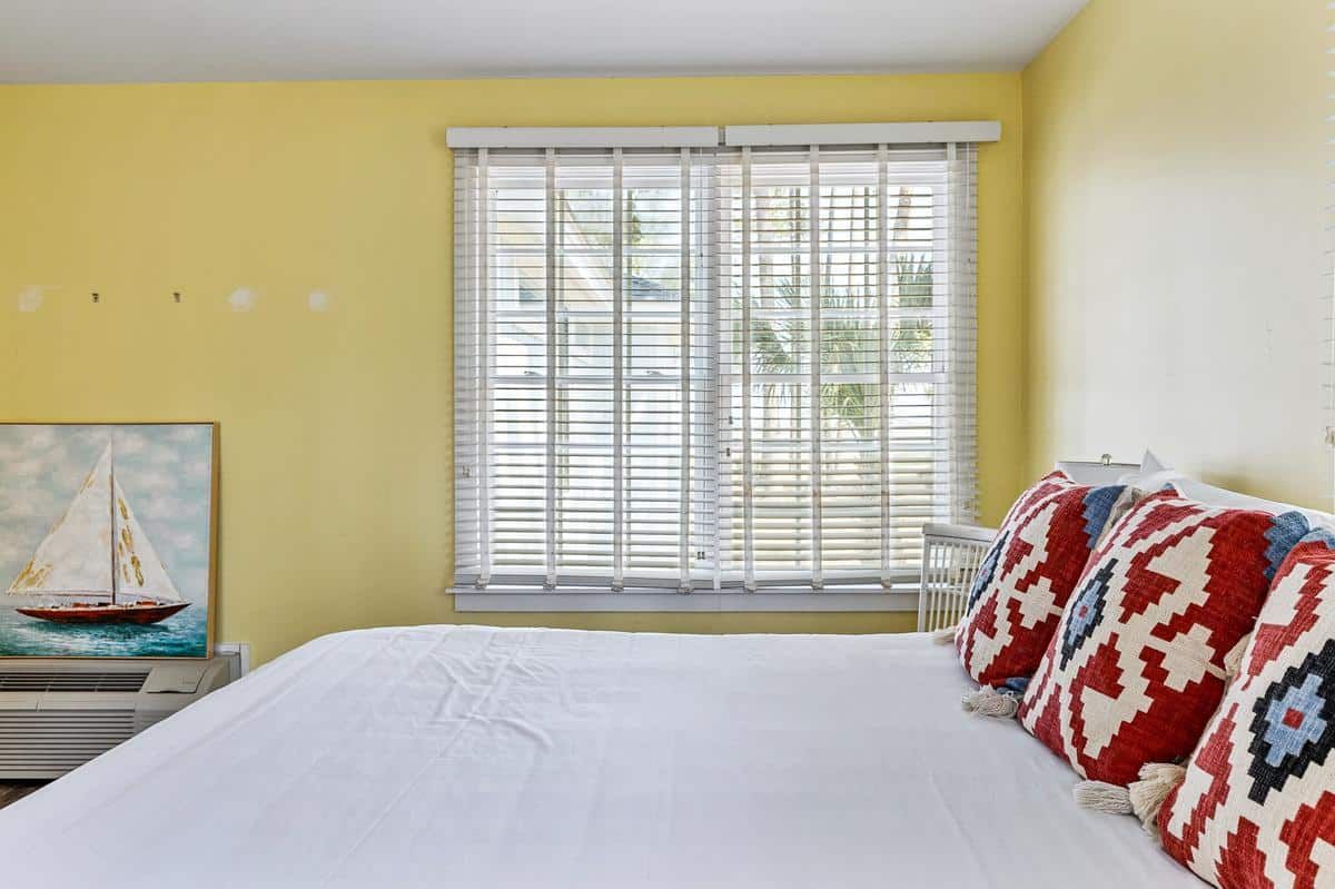 A bedroom with a large bed and a sailboat painting on the wall.