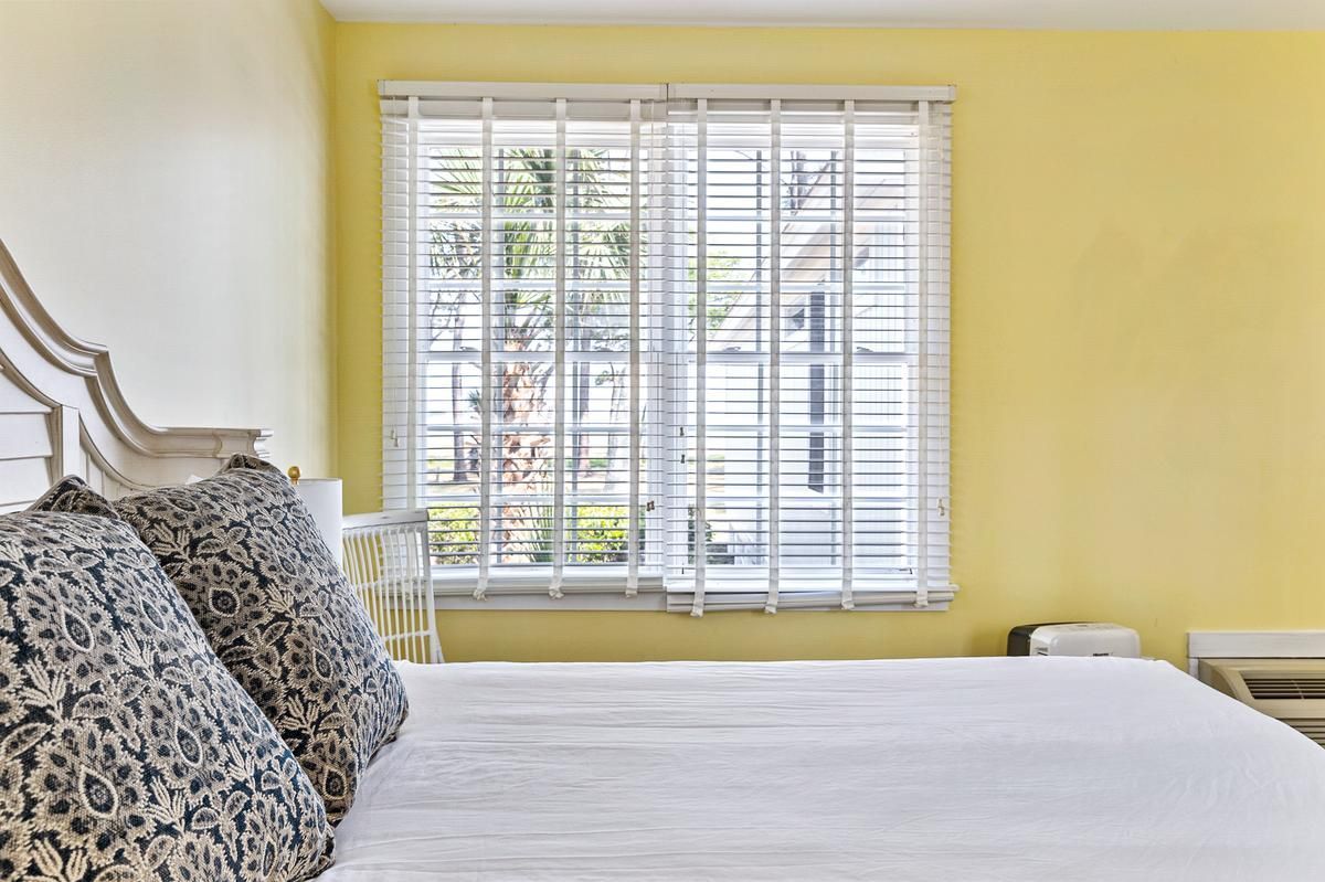 A bedroom with a bed and a window with blinds.