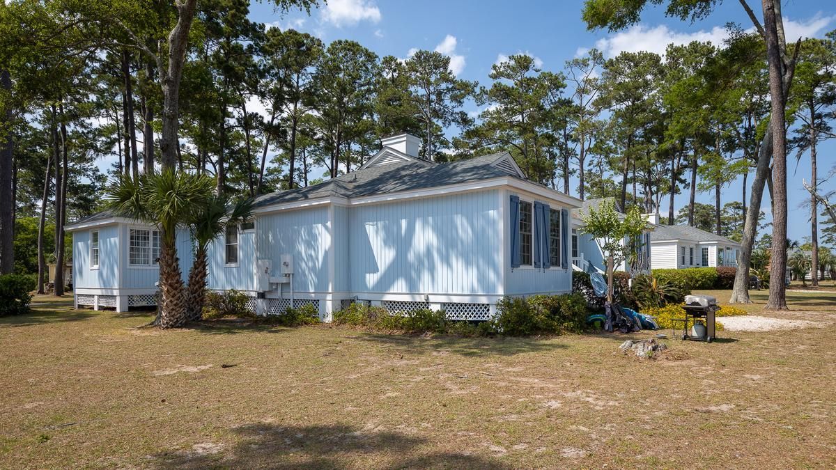 A white house is sitting in the middle of a field surrounded by trees.