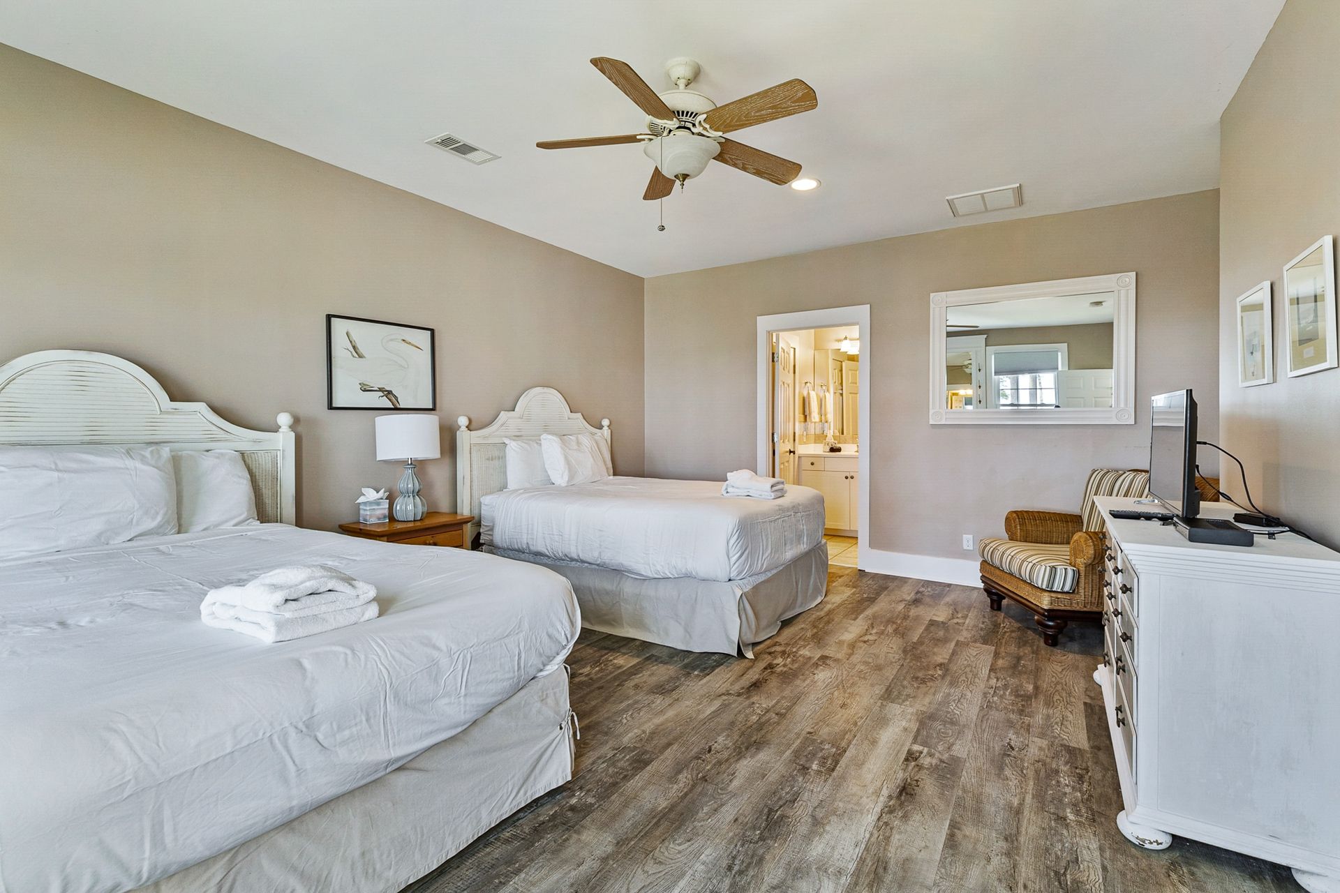 A bedroom with two beds , a dresser , a chair and a ceiling fan.