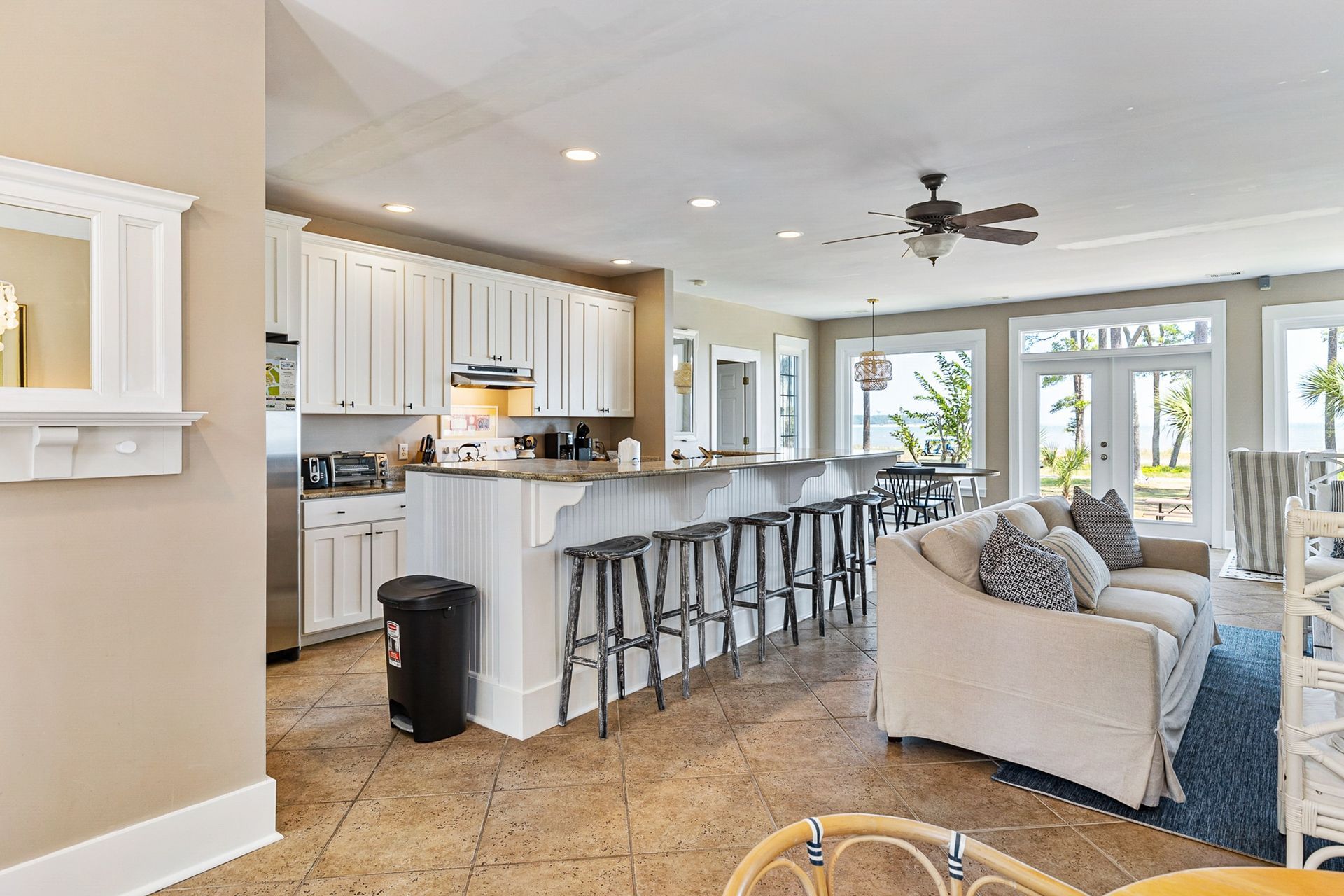 A living room filled with furniture and a kitchen with a ceiling fan.