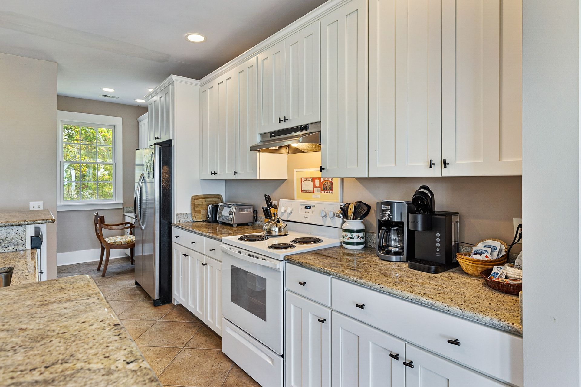 A kitchen with white cabinets and granite counter tops.