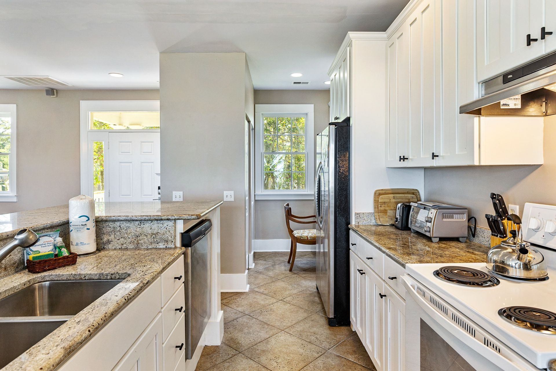 A kitchen with white cabinets , granite counter tops , stainless steel appliances and a sink.