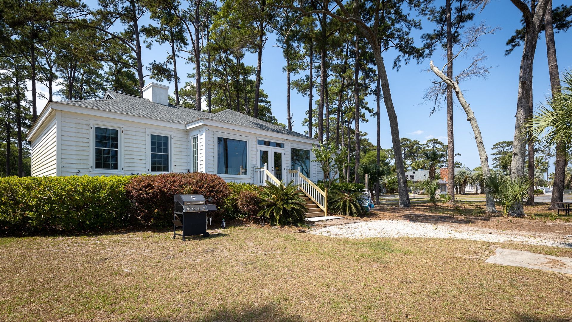 A white house is surrounded by trees on a sunny day.