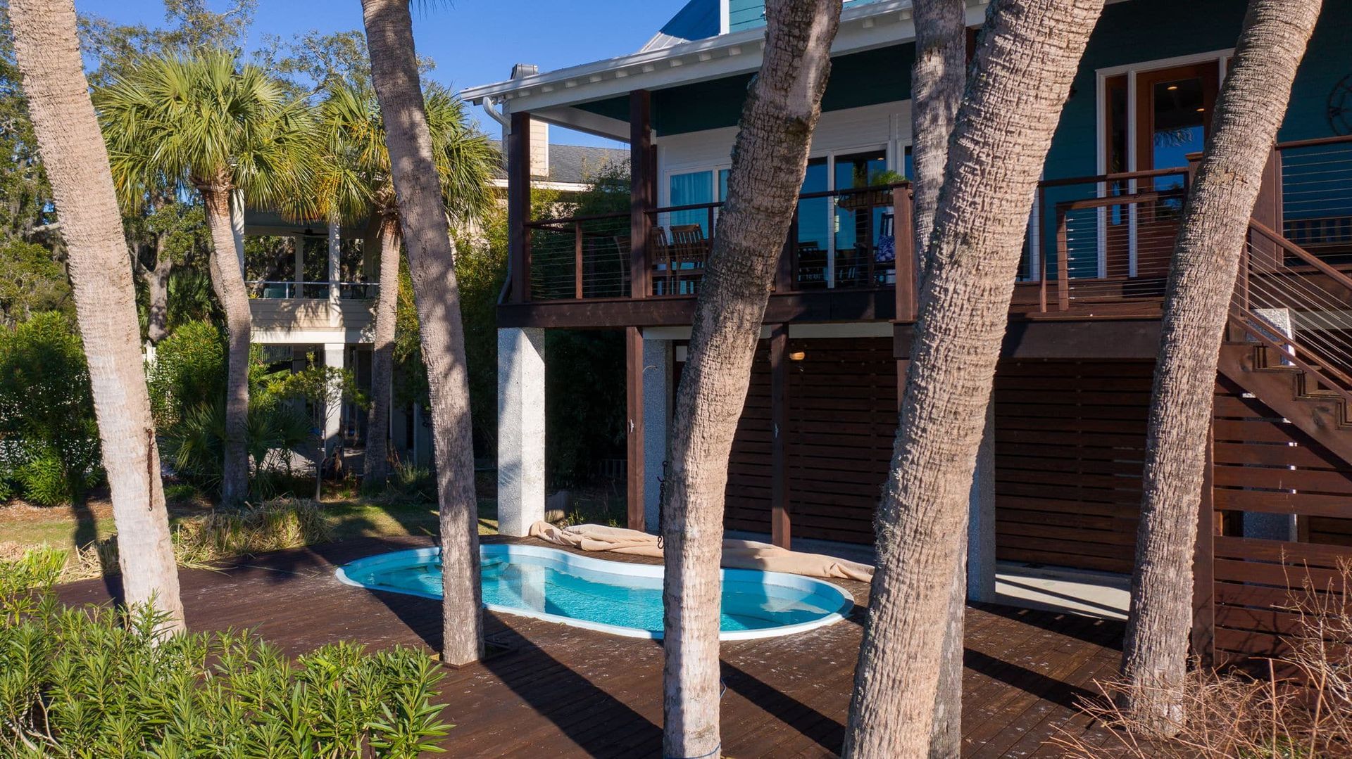 A house with a swimming pool in the backyard surrounded by palm trees.
