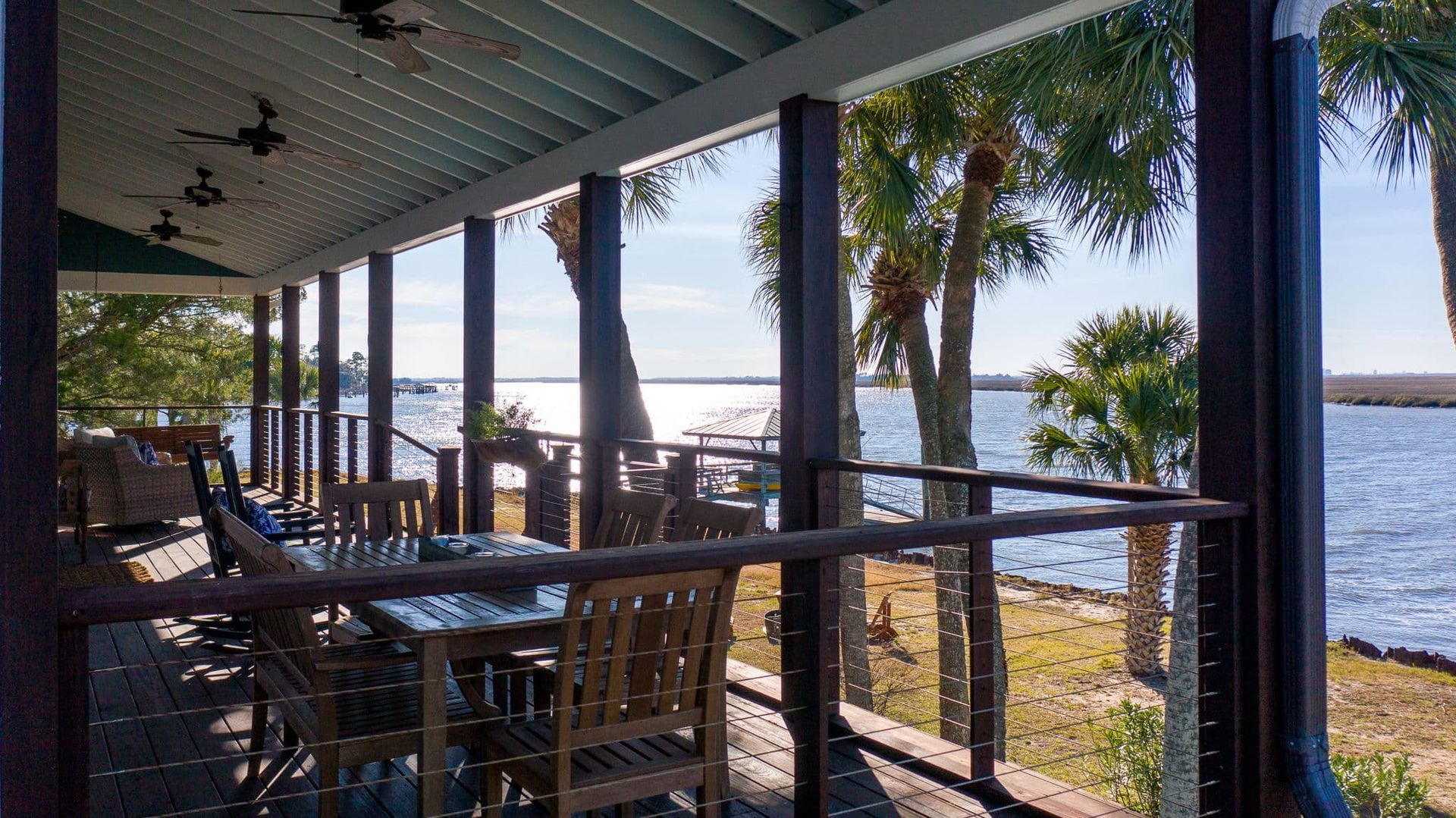 A patio with tables and chairs overlooking a body of water.