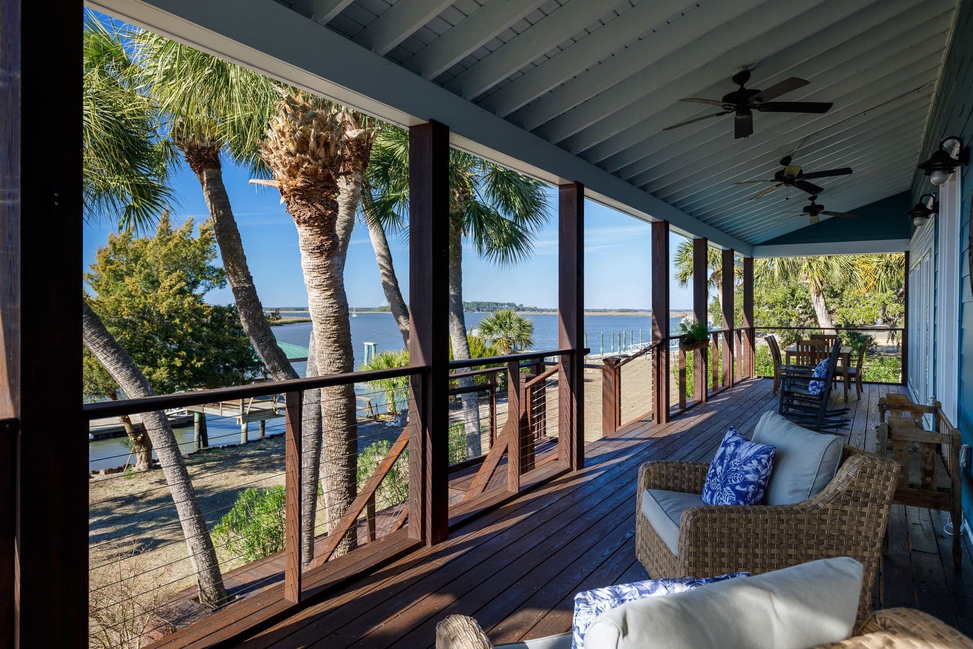 A screened in porch with a view of the ocean and palm trees.