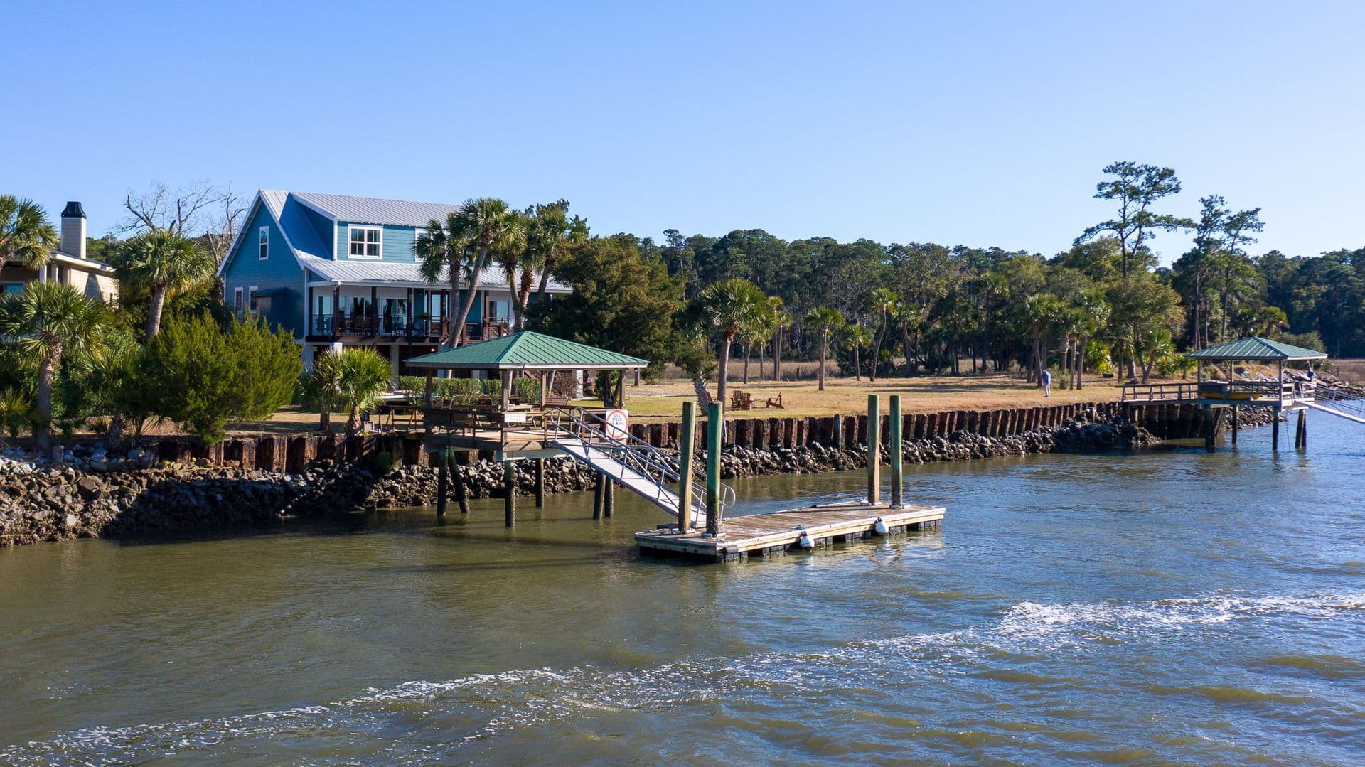 A house is sitting on the shore of a body of water next to a dock.
