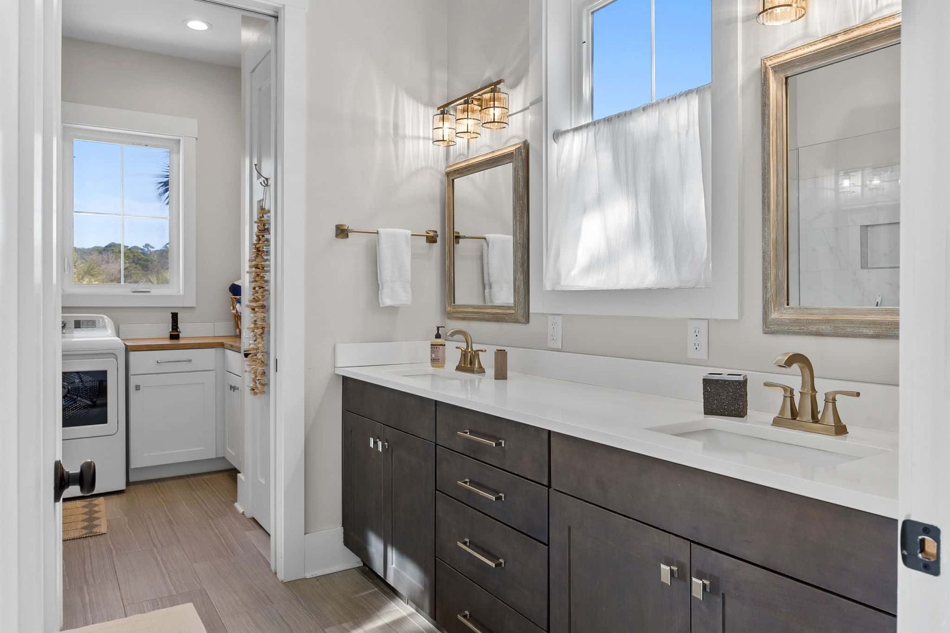 A bathroom with two sinks , two mirrors and a window.
