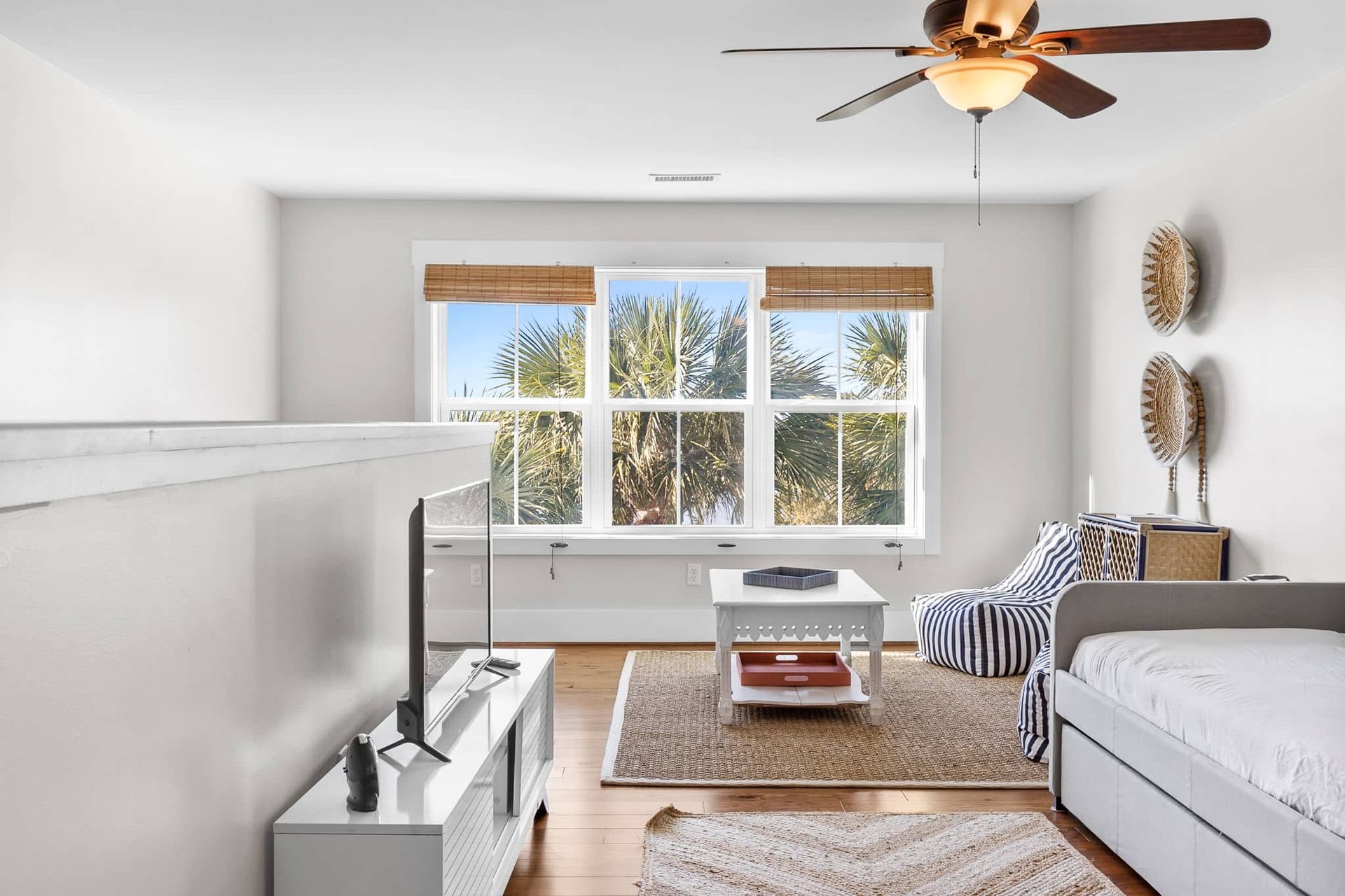 A living room with a ceiling fan and a bed