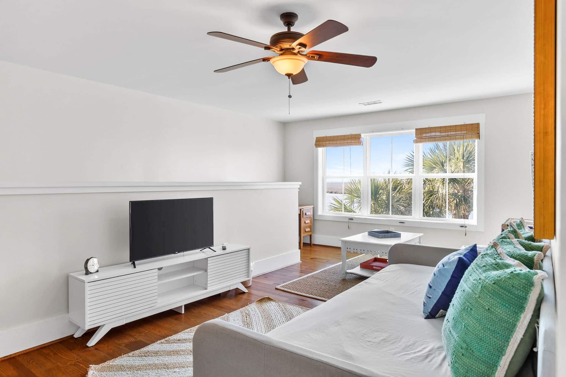 A living room with a couch , television , and ceiling fan.