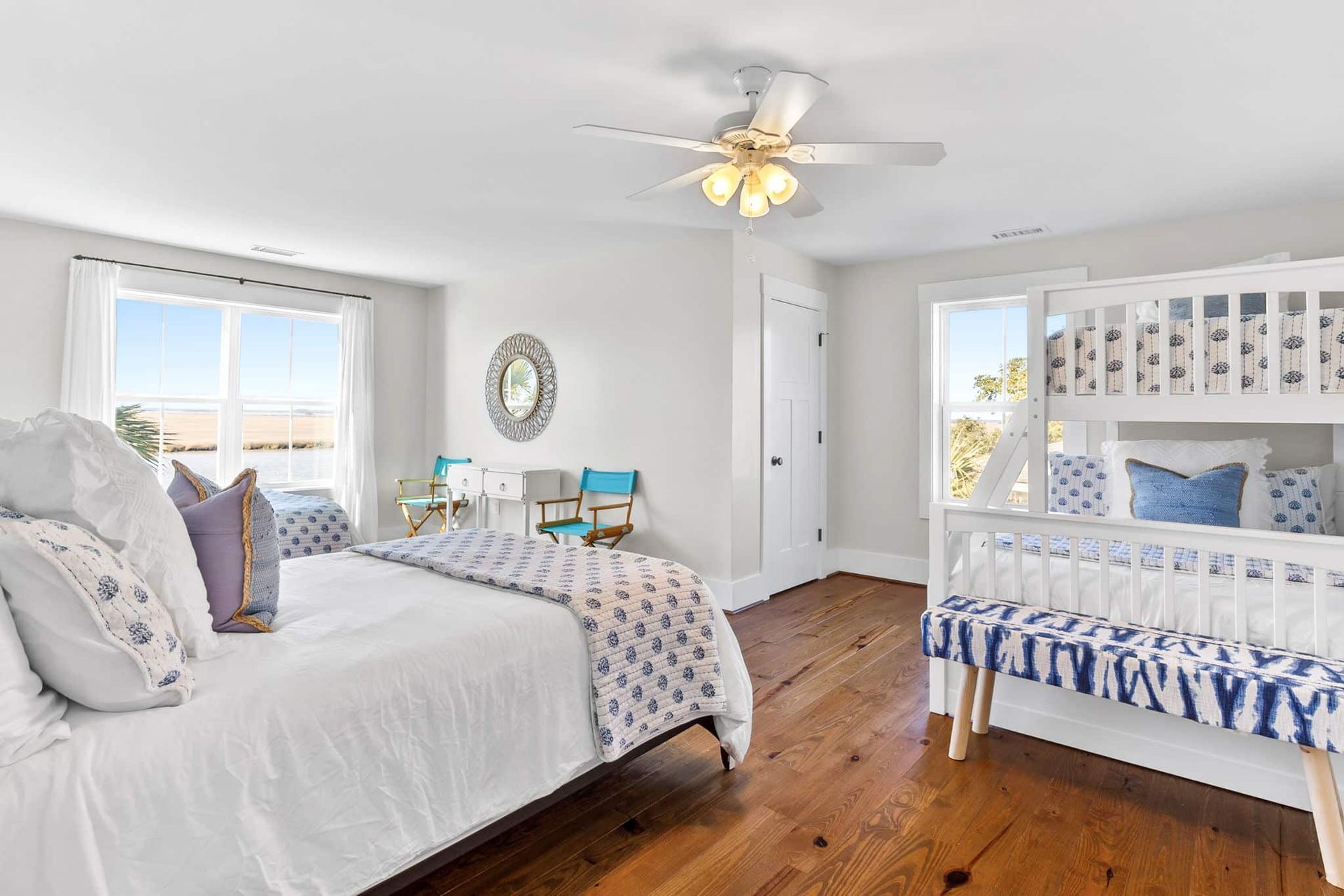 A bedroom with two beds , a bunk bed and a ceiling fan.