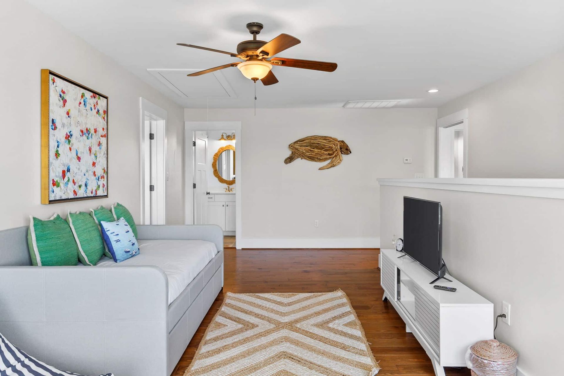 A living room with a couch , television , and ceiling fan.