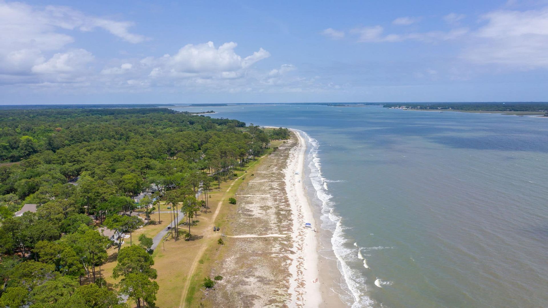An aerial view of a beach surrounded by trees and a body of water.