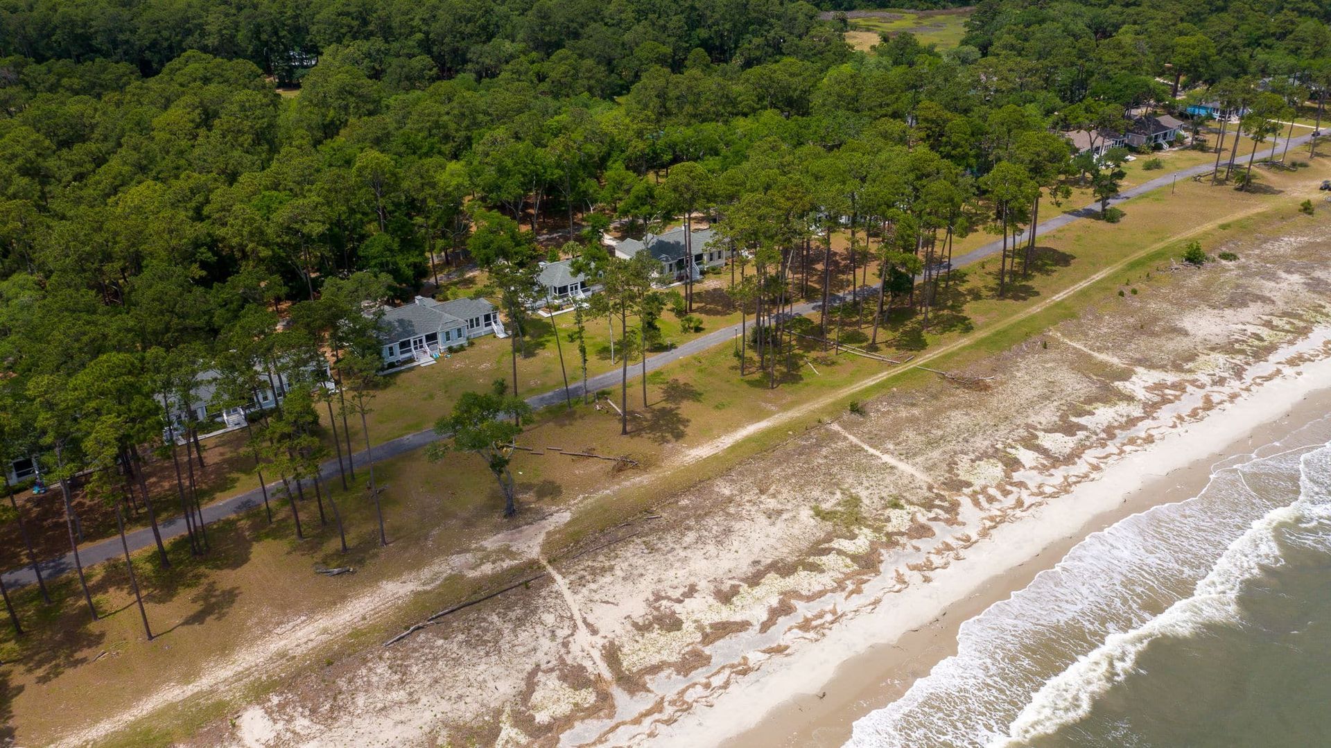 An aerial view of a beach surrounded by trees and a body of water.