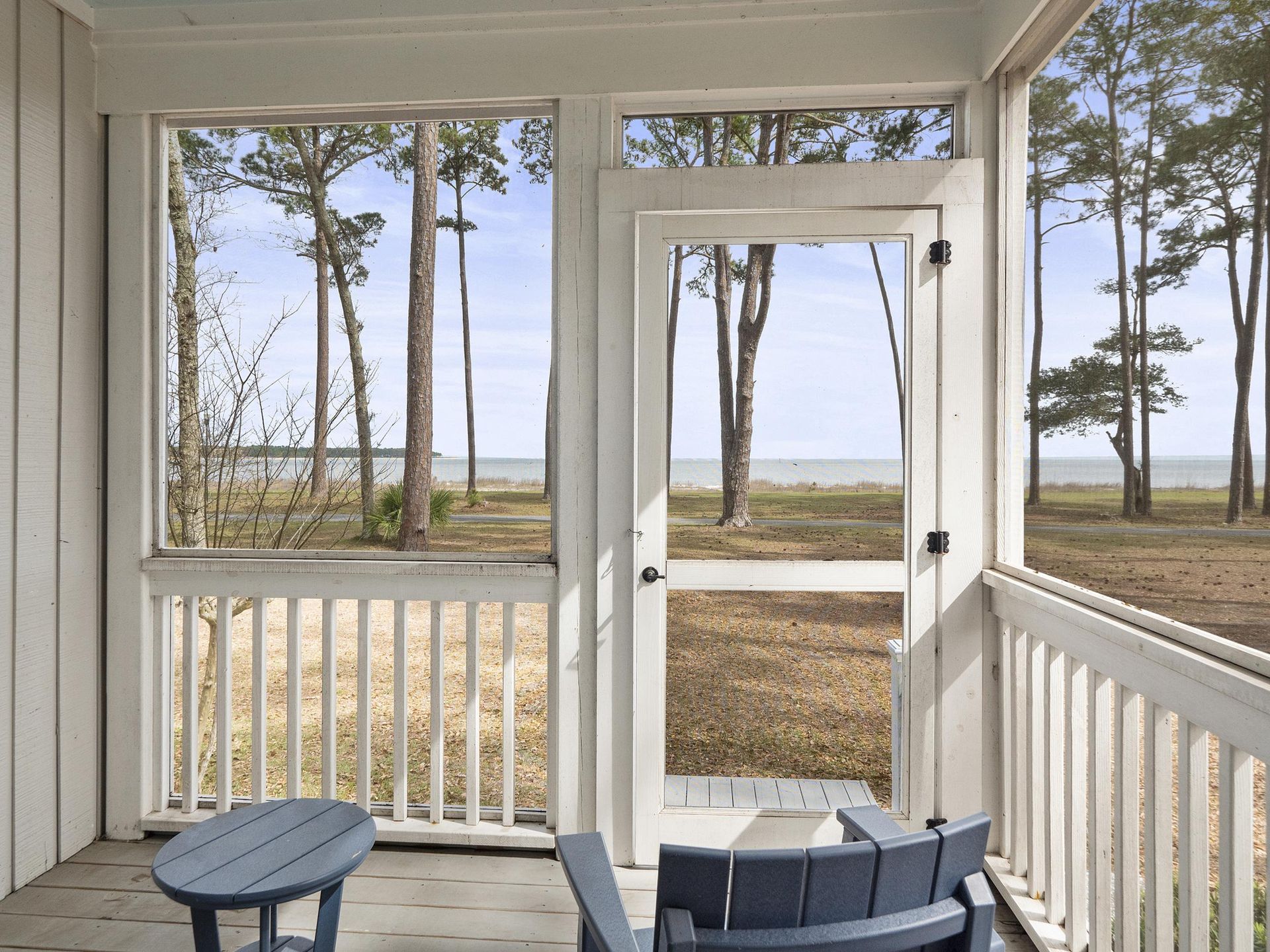 A screened in porch with a view of the ocean and trees