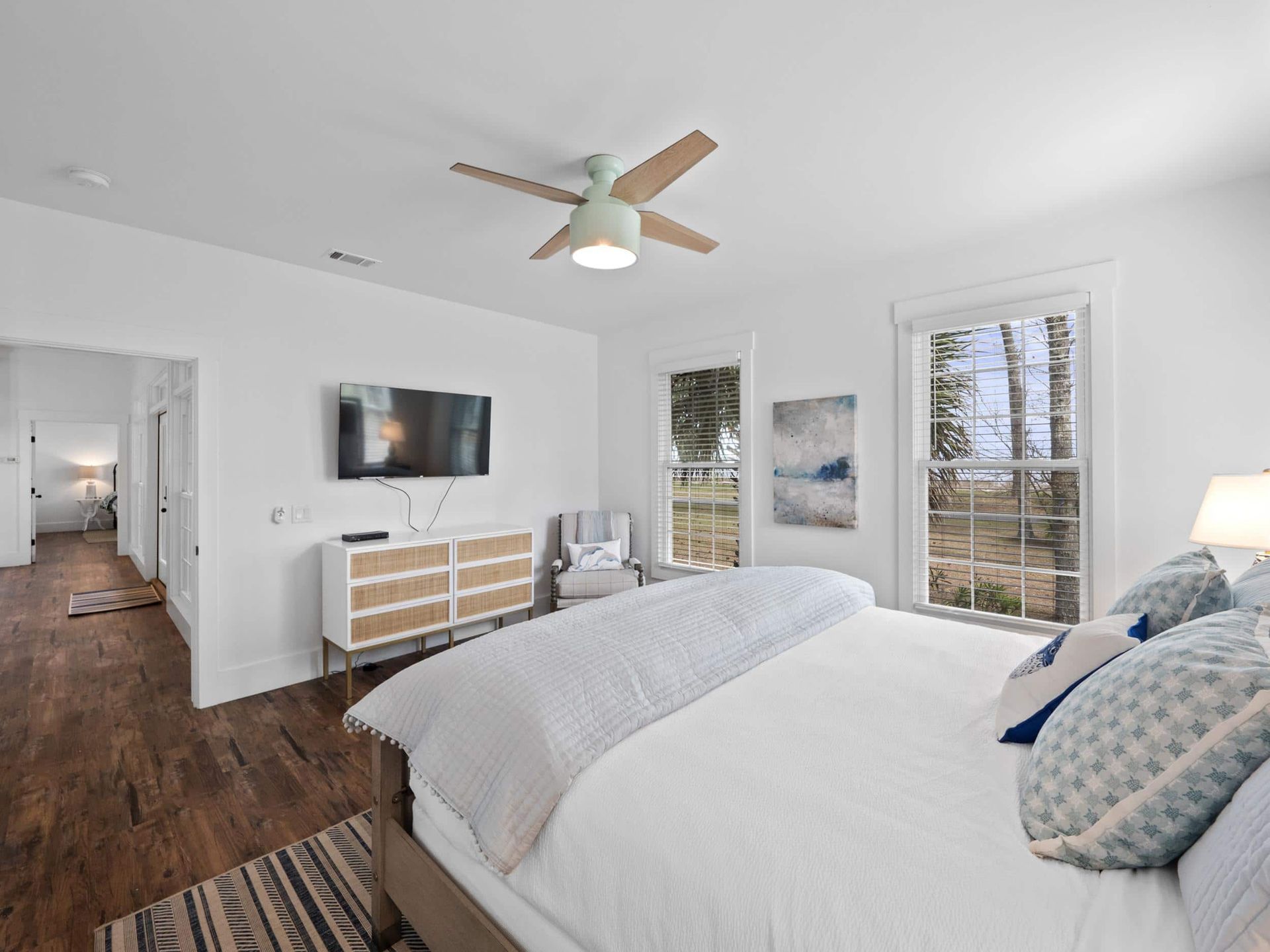A bedroom with a bed , television , dresser and ceiling fan.