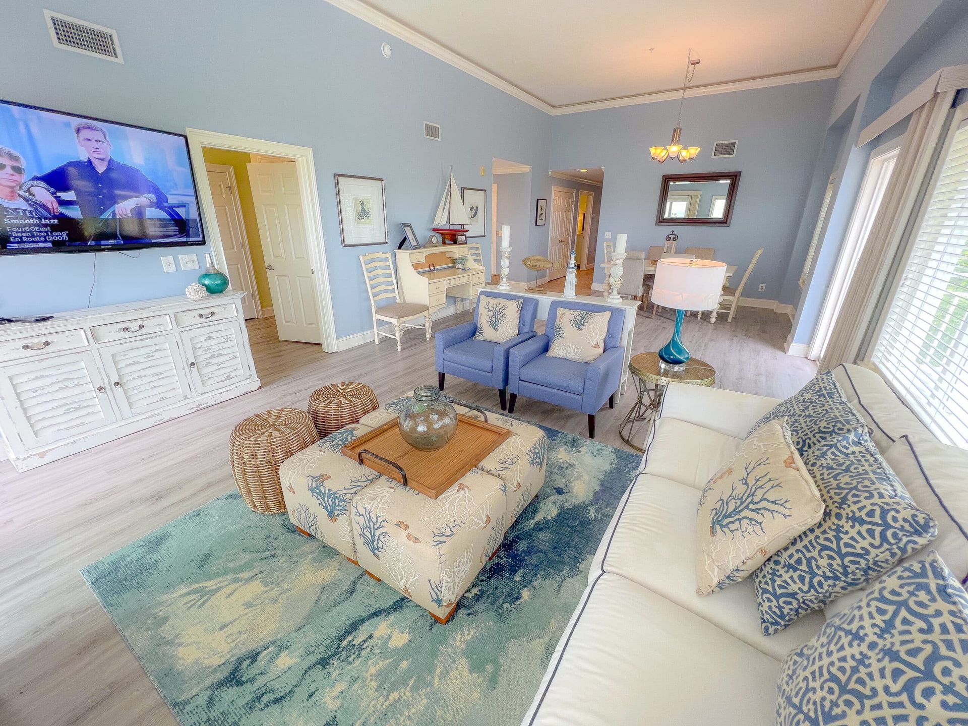 A living room with a couch , chairs , and a flat screen tv.