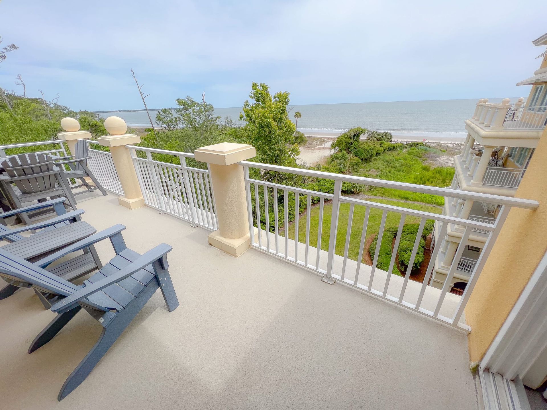 A balcony with chairs and a railing overlooking the ocean