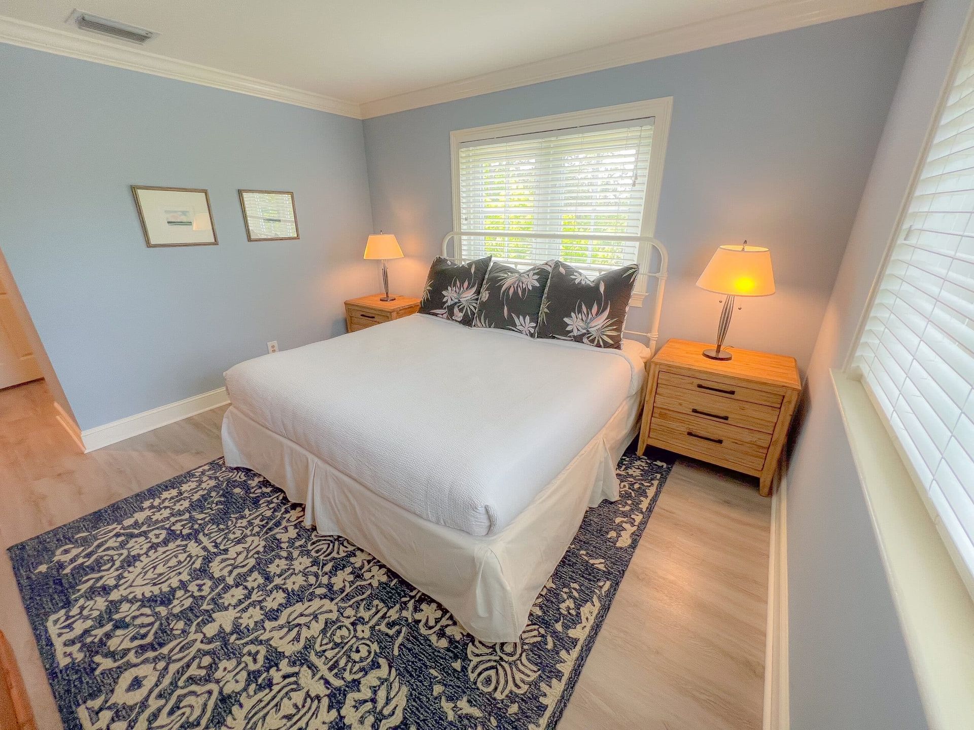 A bedroom with a king size bed , nightstands , lamps and a rug.