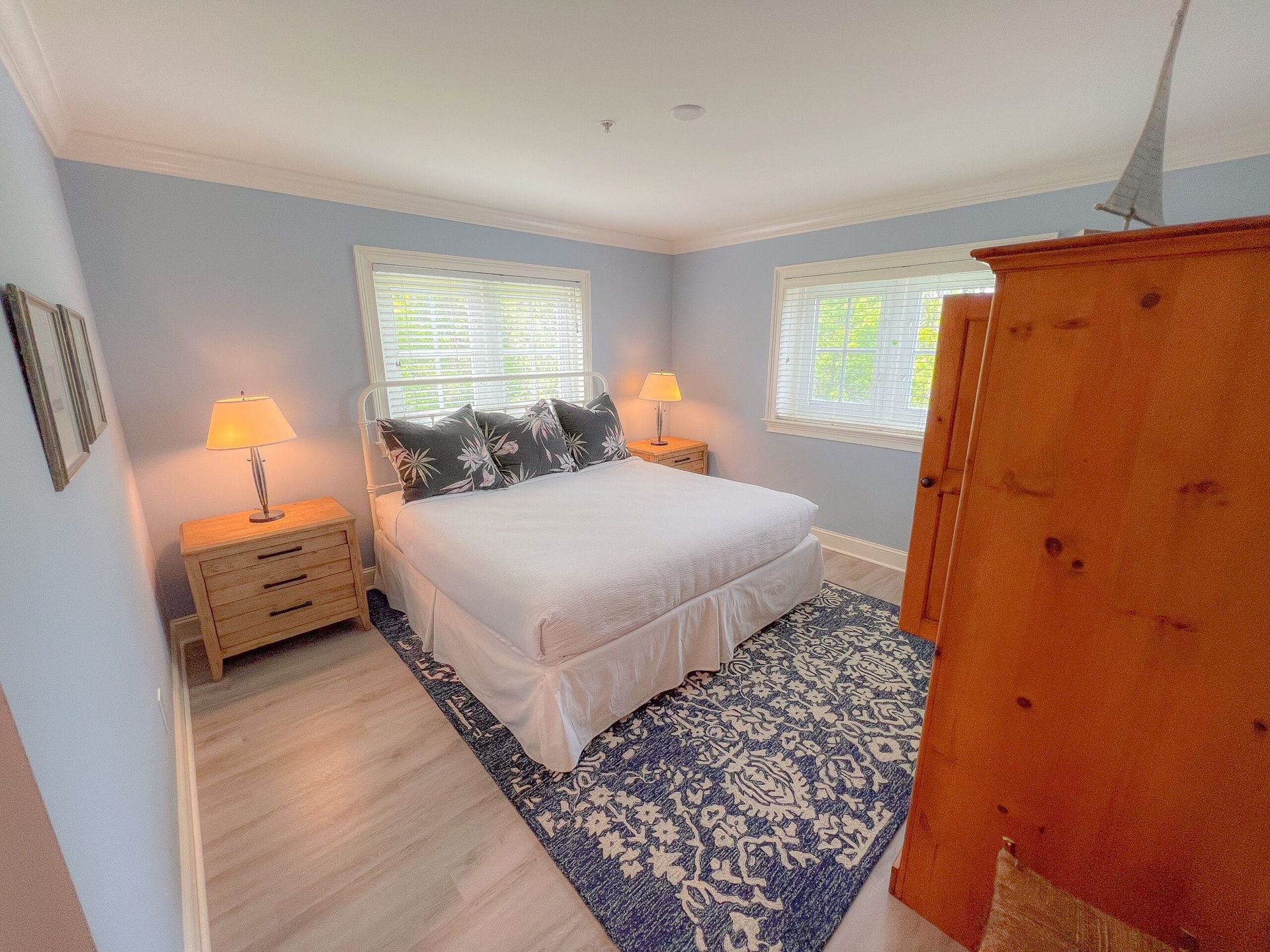 A bedroom with a king size bed , dresser , nightstand and rug.