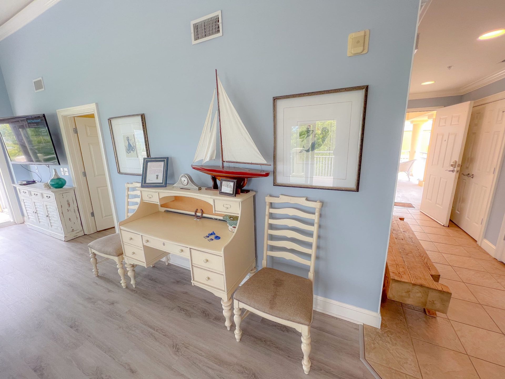 A room with a desk and chairs and a sailboat on top of it