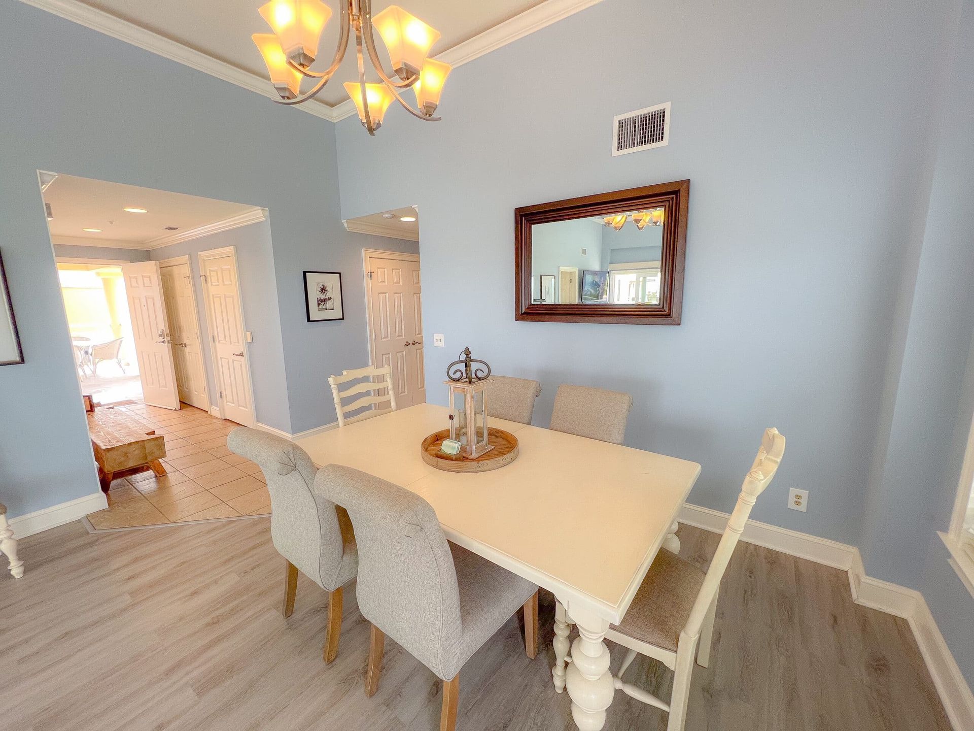 A dining room with a table and chairs and a mirror on the wall.