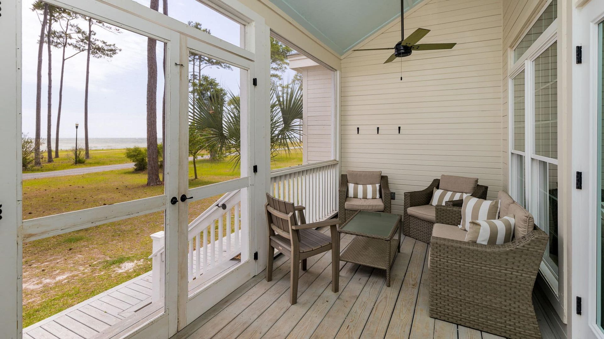A screened in porch with furniture and a ceiling fan.