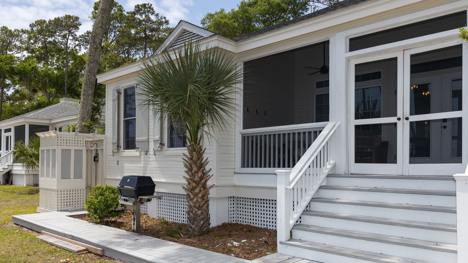 A white mobile home with a screened in porch and stairs.