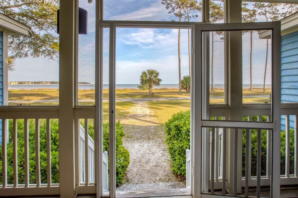 A screened in porch with a view of a beach.