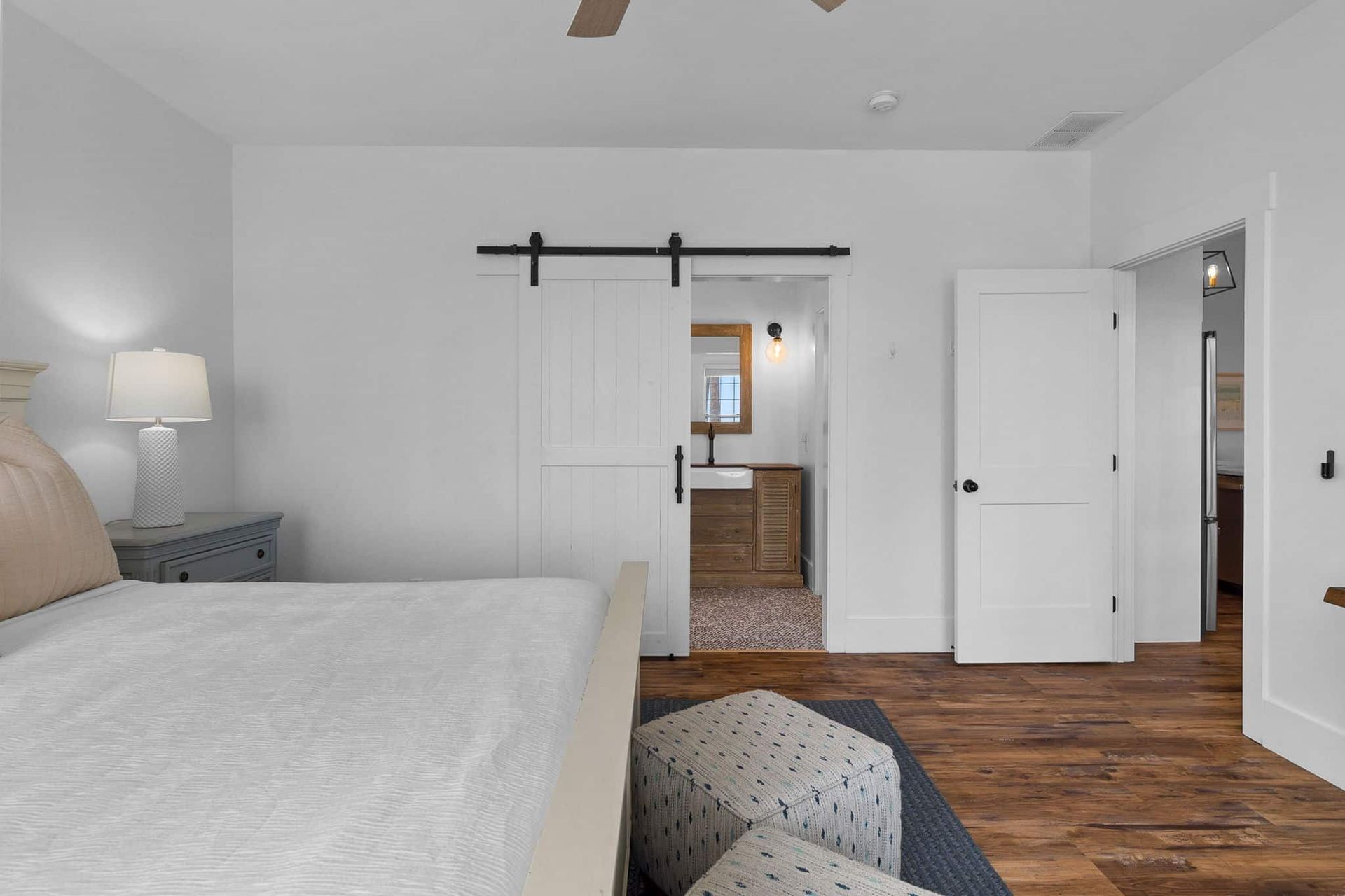 A bedroom with a sliding barn door leading to a bathroom.