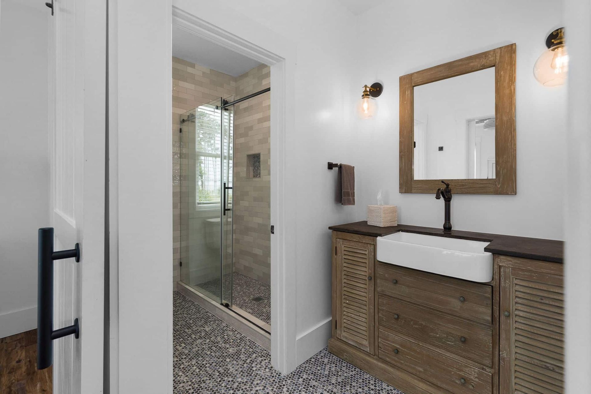 A bathroom with a sink , mirror and walk in shower.