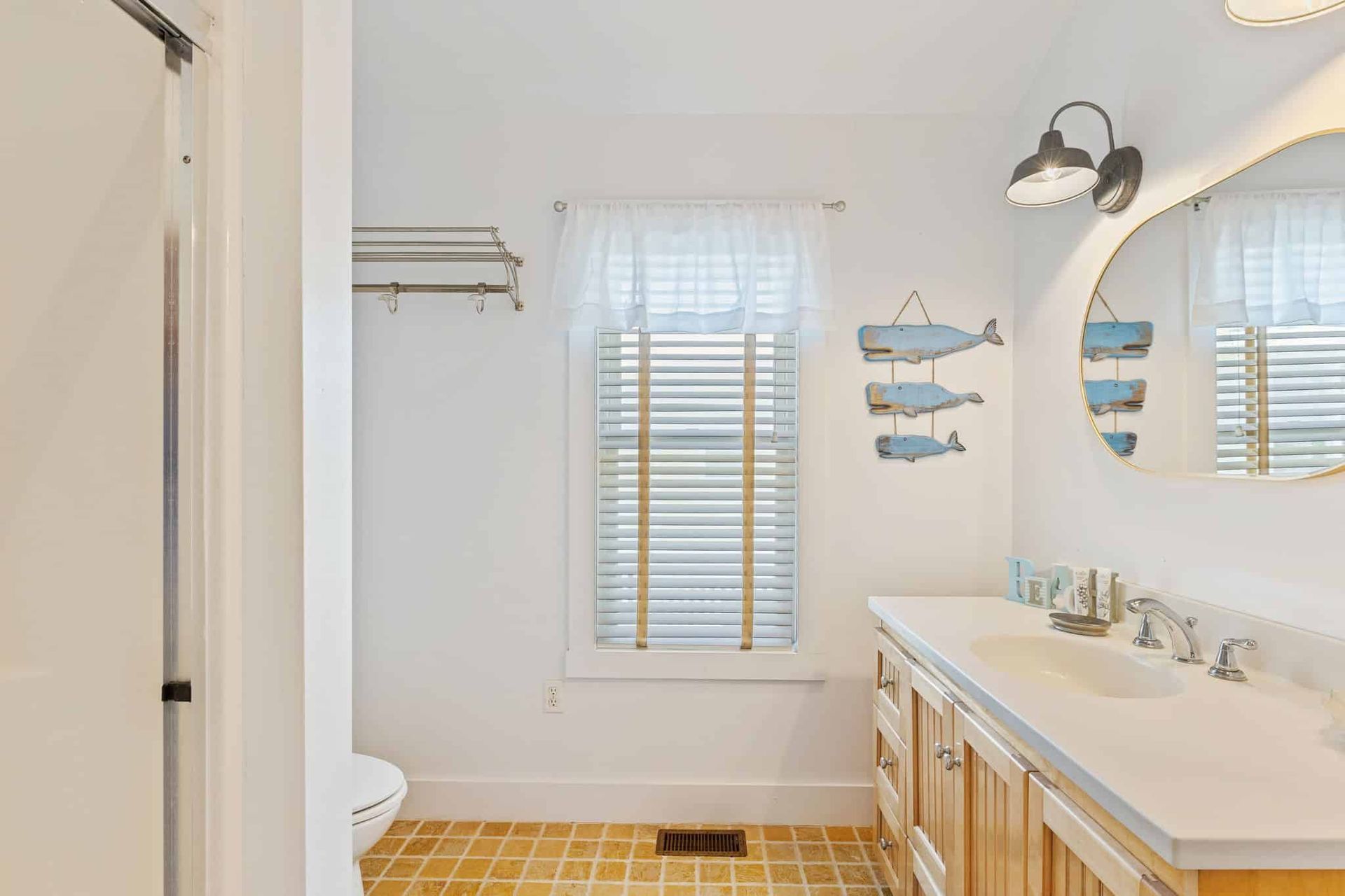 A bathroom with a sink , toilet , mirror and window.