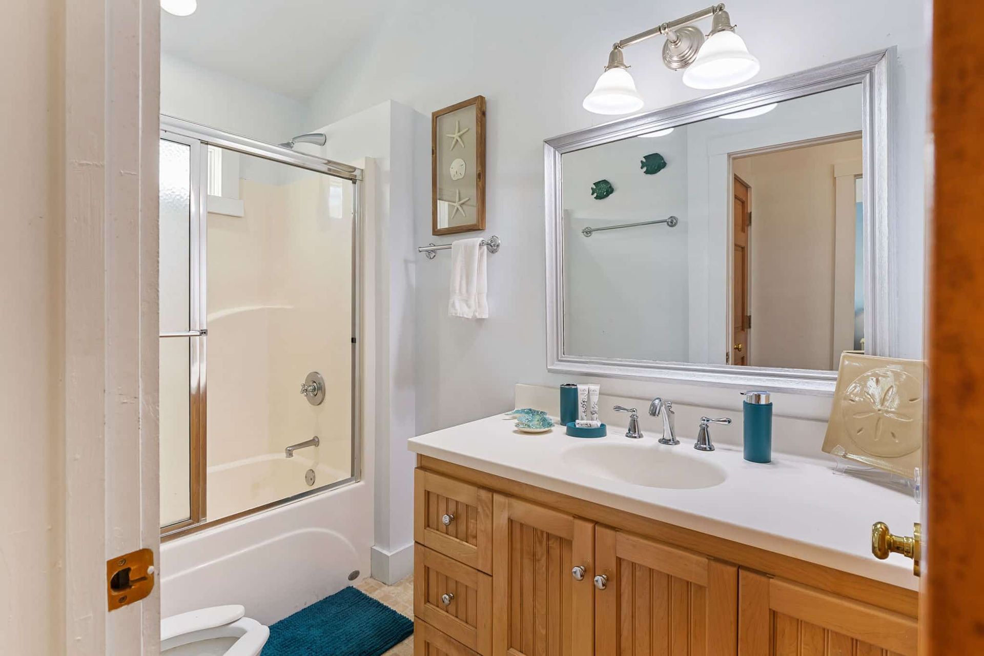 A bathroom with a sink , toilet , shower and mirror.