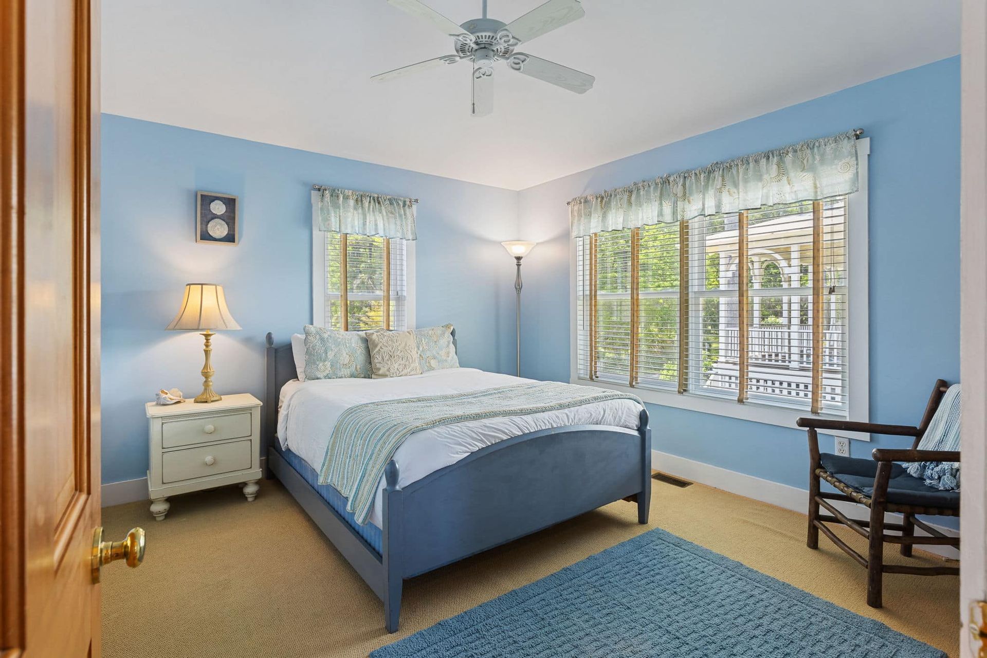A bedroom with a bed , nightstand , chair and ceiling fan.