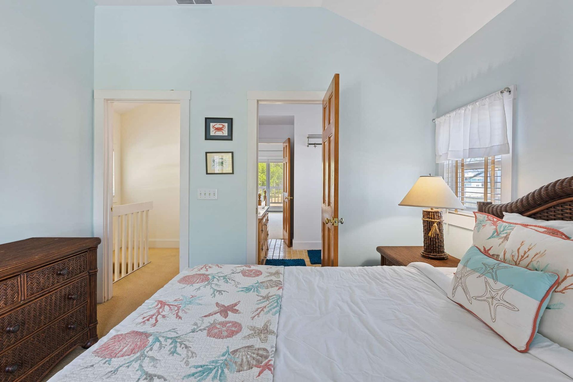 A bedroom with a king size bed , dresser , lamp and window.