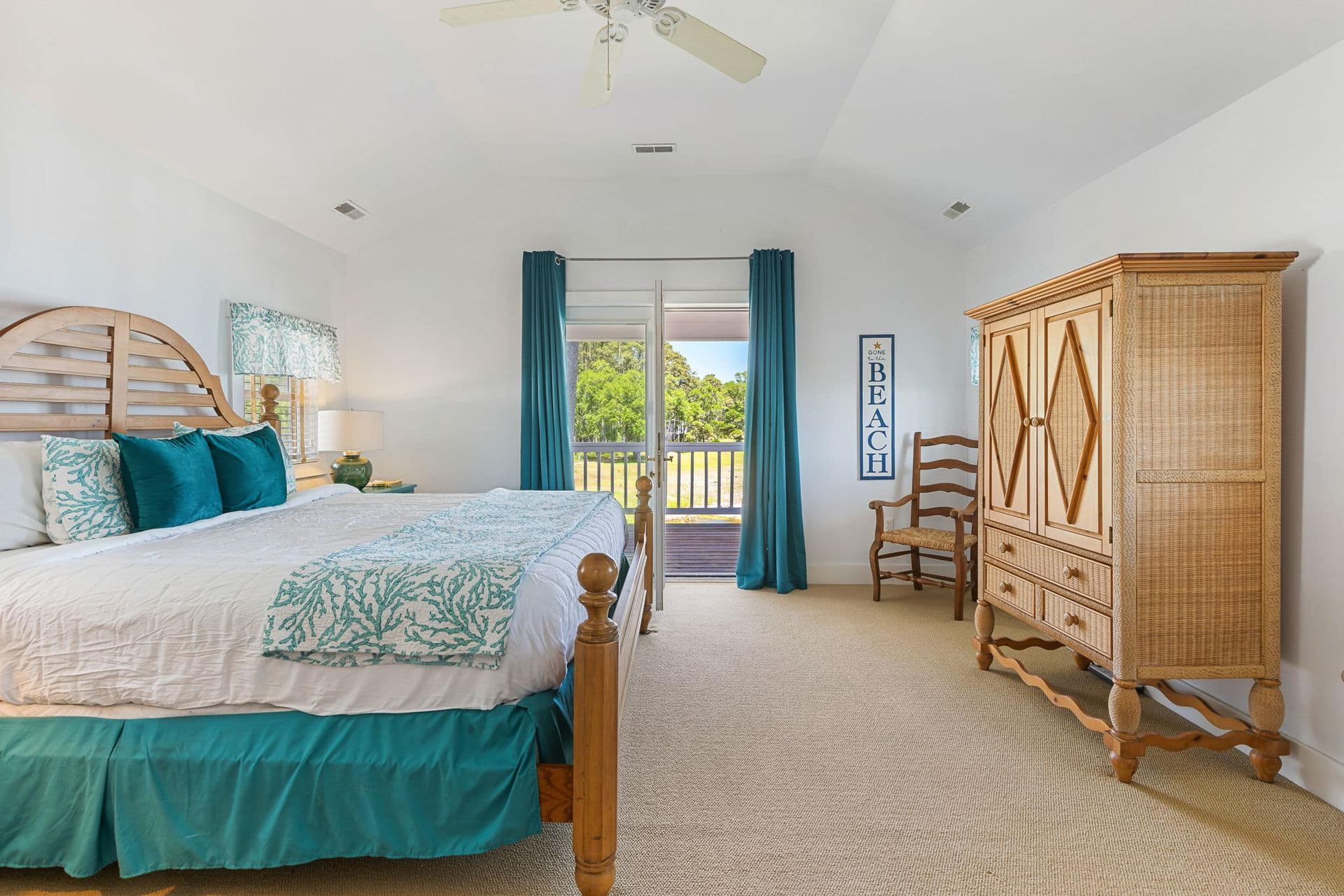 A bedroom with a king size bed , dresser , chair and sliding glass door.