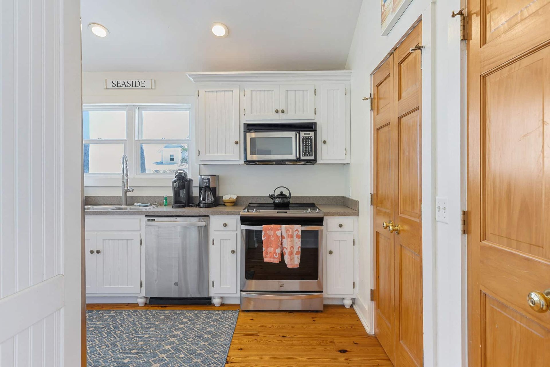 A kitchen with white cabinets , stainless steel appliances , and wooden floors.