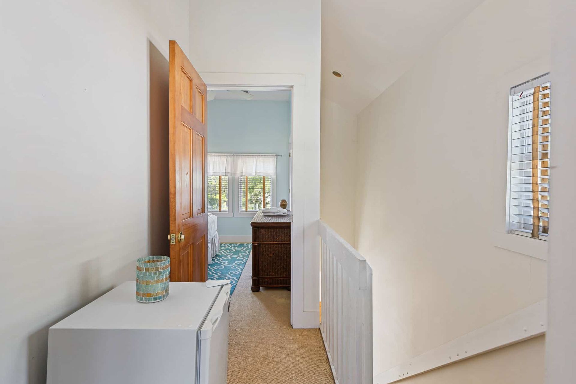 A hallway in a house with a refrigerator and a window.